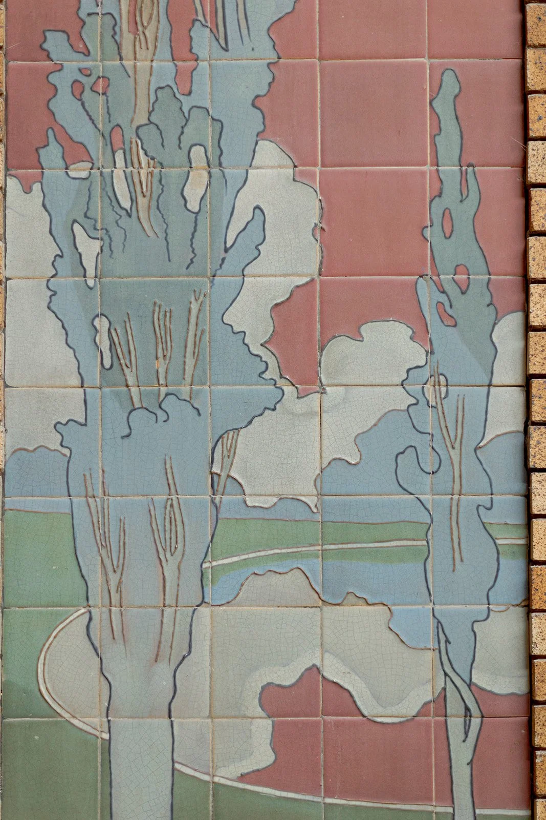 Close view of Cafe Brauer's original Arts and Crafts tile mural depicting stylized trees and a landscape in muted tones.