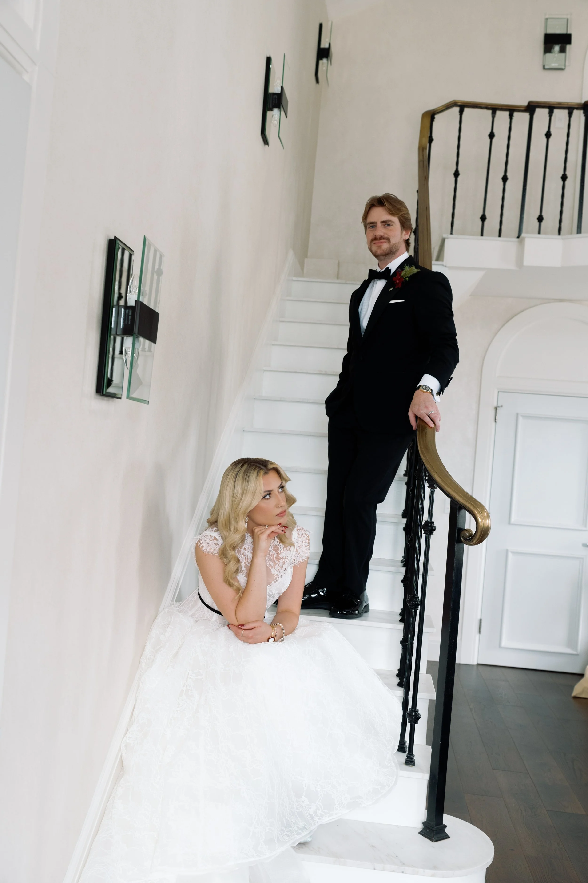 Bride sits on the staircase looking up at the groom standing above her