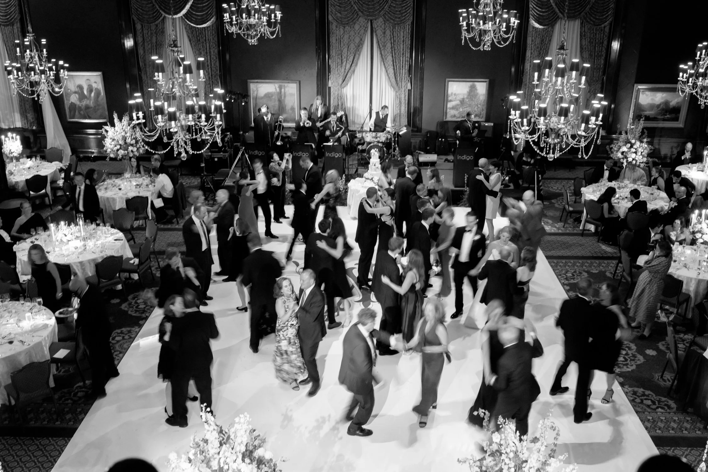 Black and white aerial of the Union League Club grand ballroom at full reception energy, guests filling the floor beneath rows of glittering chandeliers.
