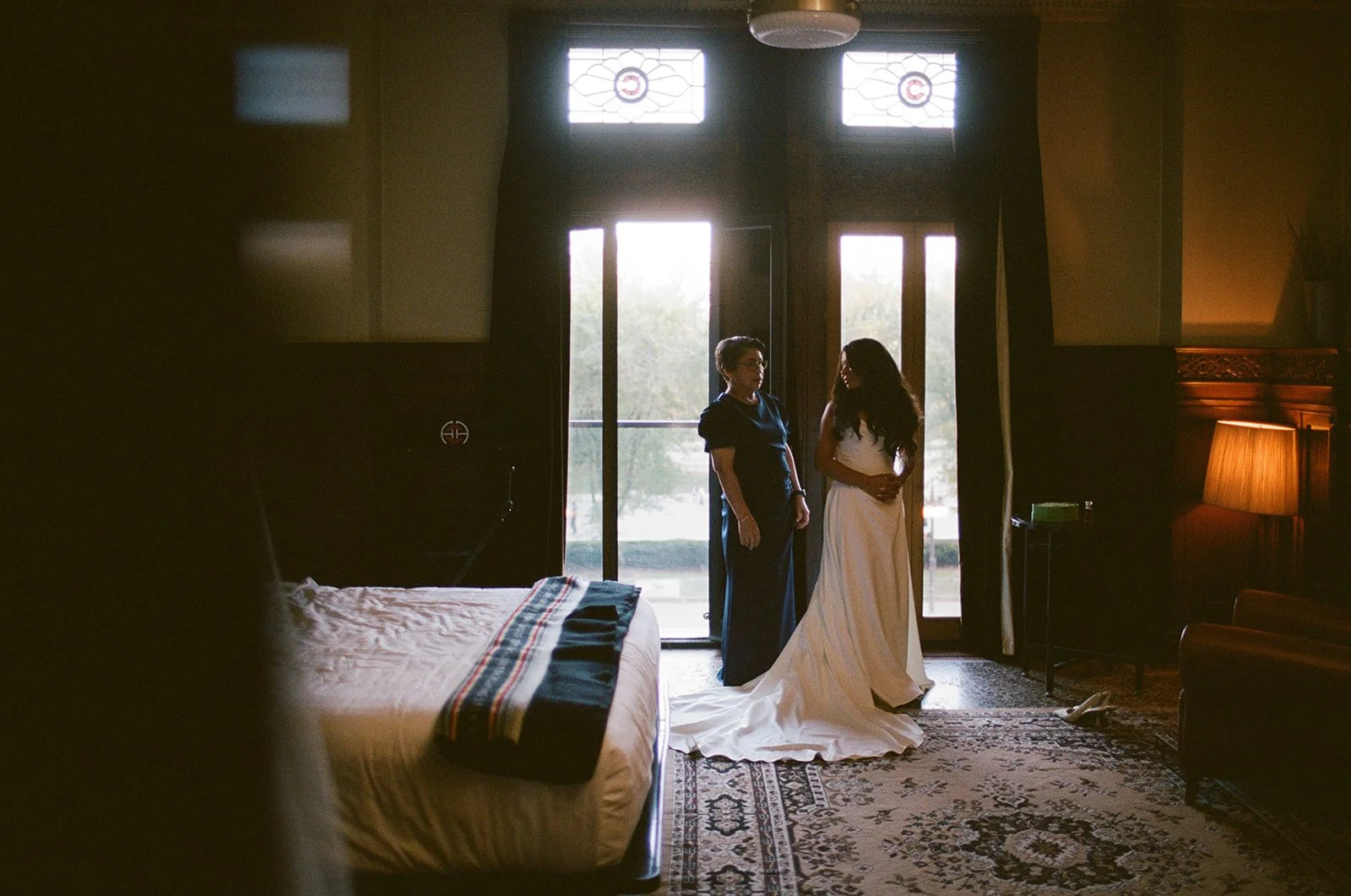 Sarah and Brennan share a tender moment in the Chicago Athletic Association's elegant room with arched stained-glass windows during getting ready. Shot on film by a Chicago film wedding photographer.