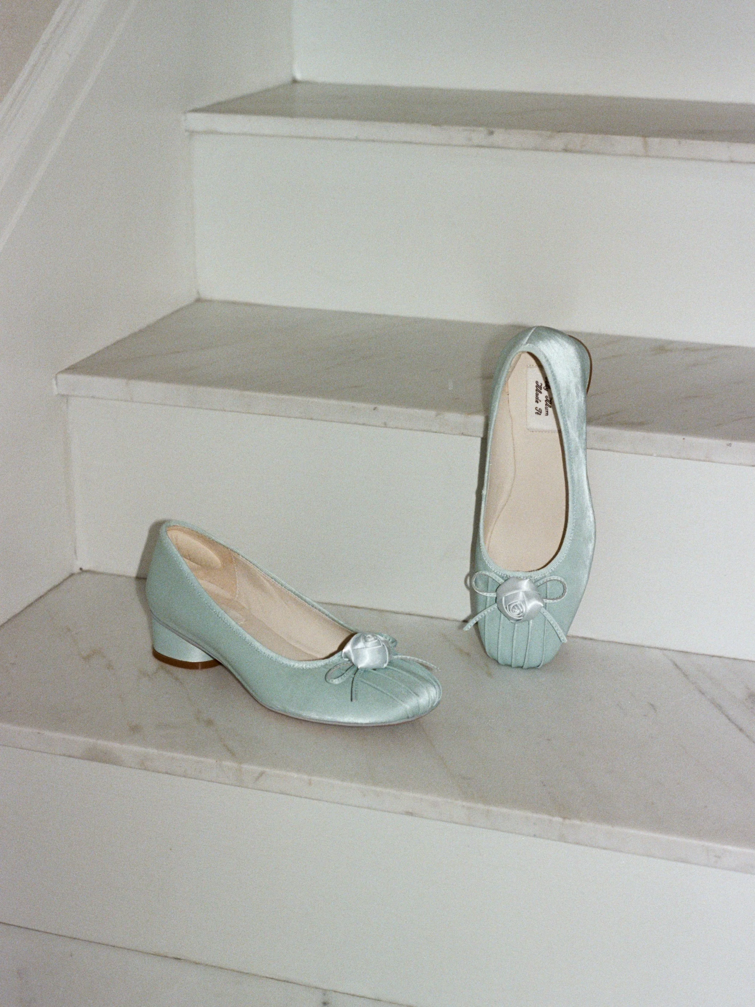 Pale blue bridal flats and heels rest on a white marble staircase