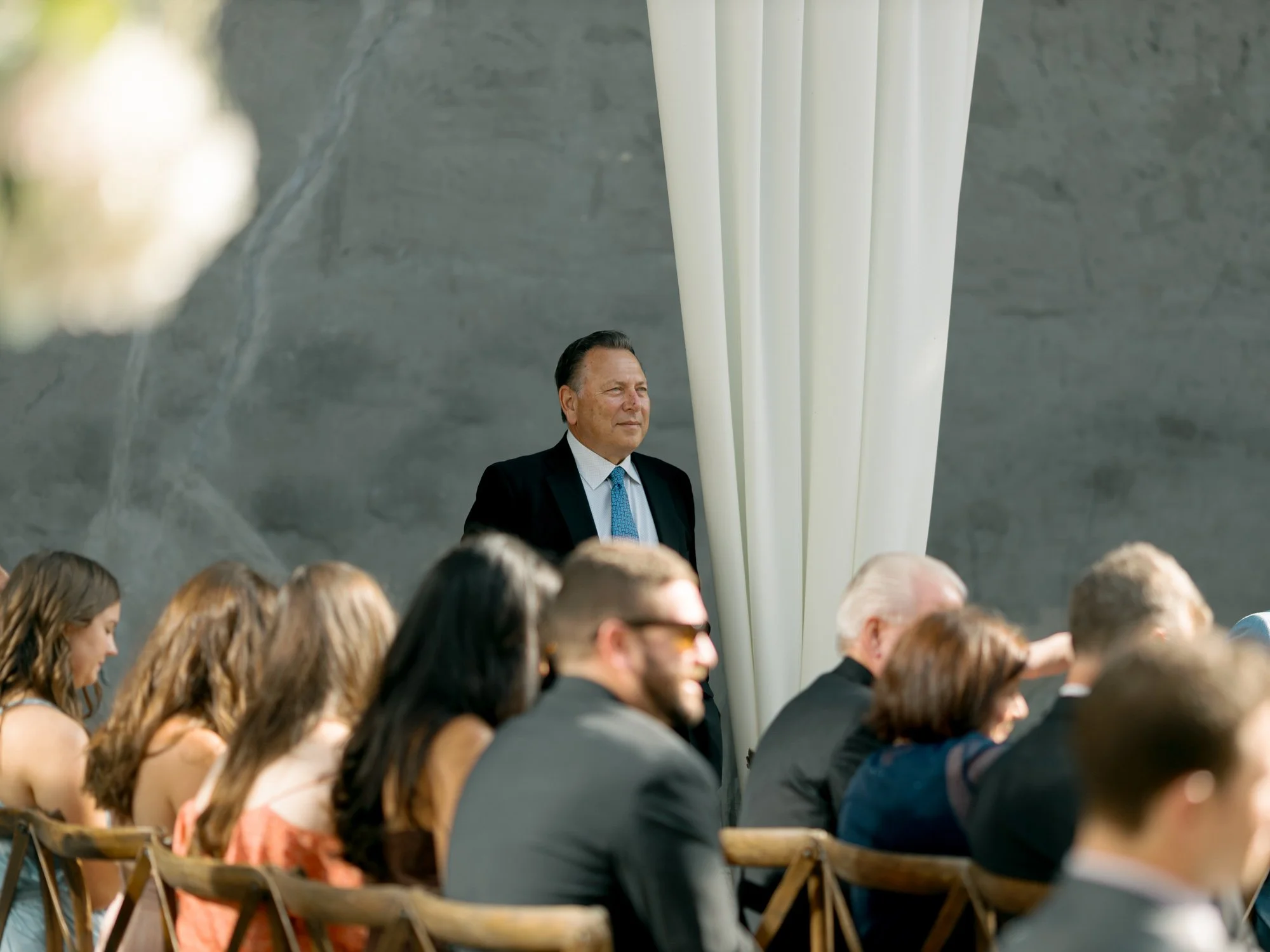 A proud and smiling older gentleman stands at the edge of the ceremony aisle at the Chicago Illuminating Company, beaming with joy during the celebration.