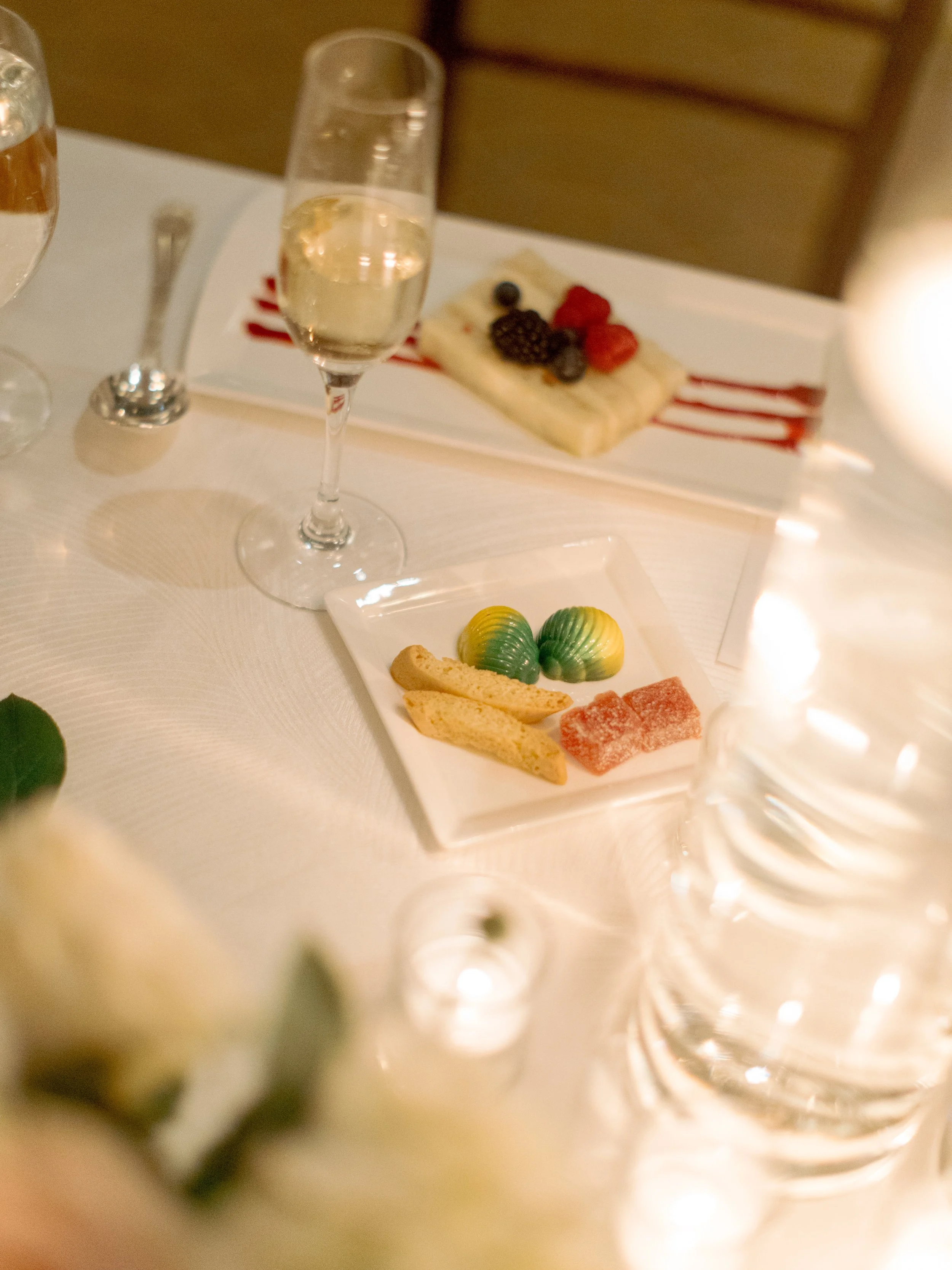 Dessert plate of petit fours and berries beside a glass of champagne at The Peninsula Chicago wedding reception