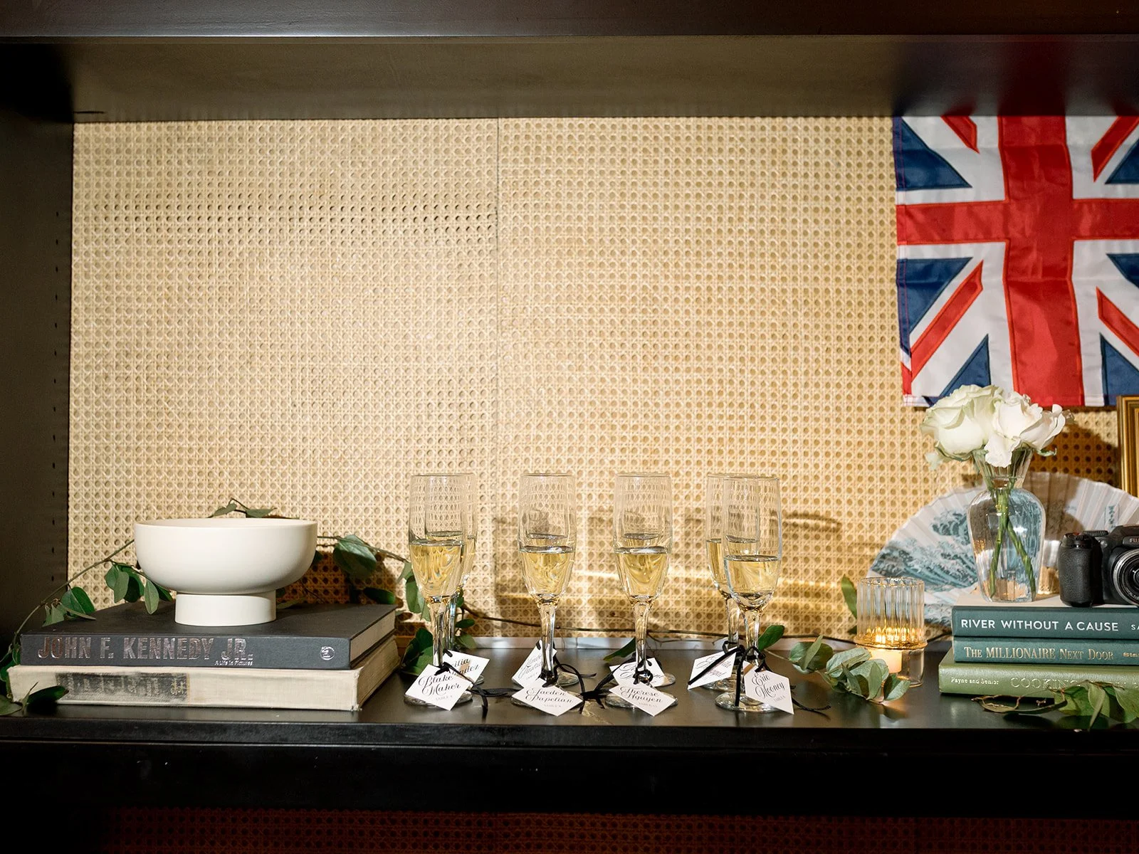 A styled engagement detail shot featuring a Union Jack flag, stacked books, white flowers, and vintage decor. Shot on film by a Chicago wedding photographer.