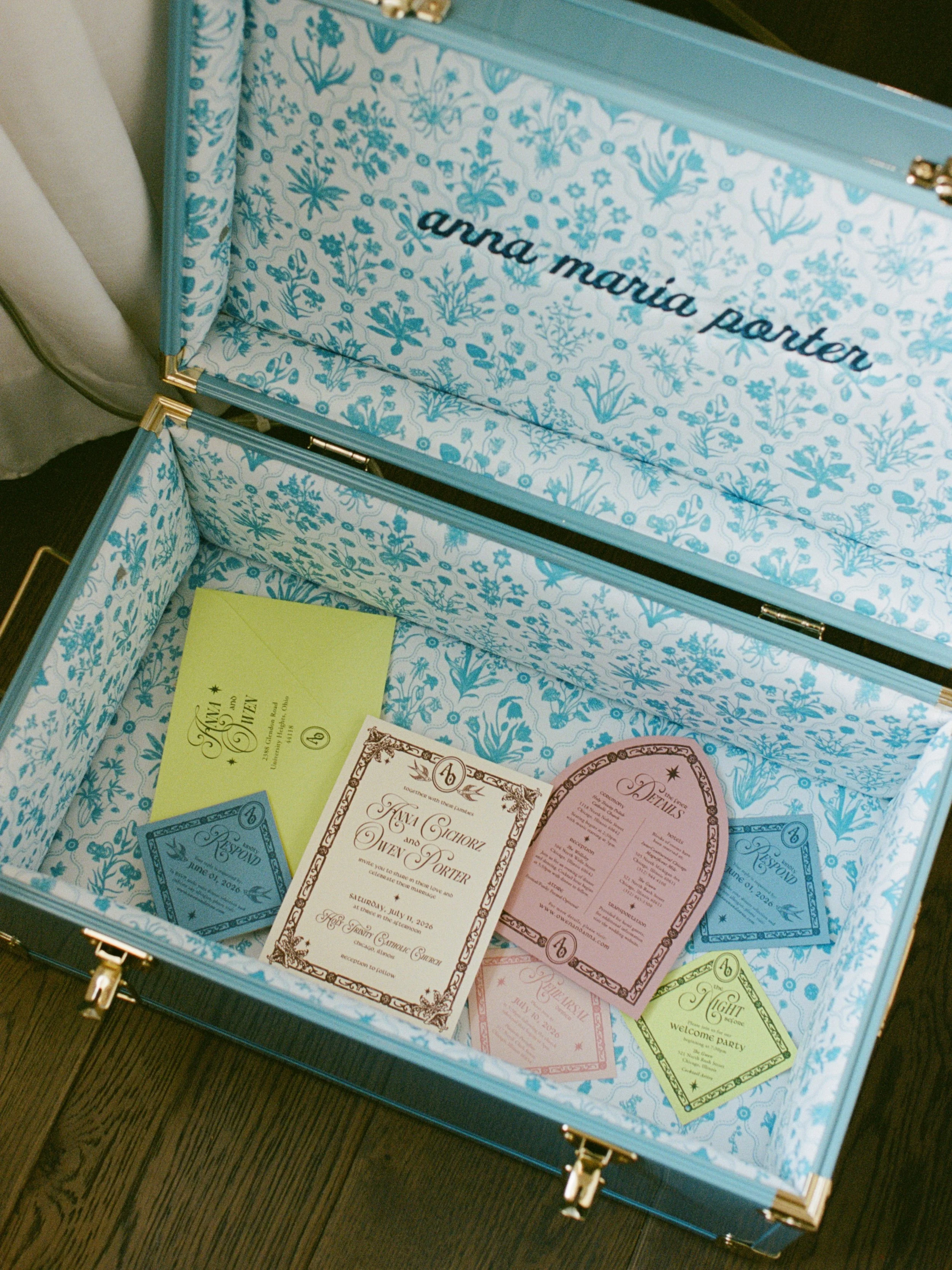 Vintage blue trunk monogrammed Anna Maria Porter holds wedding stationery and place cards