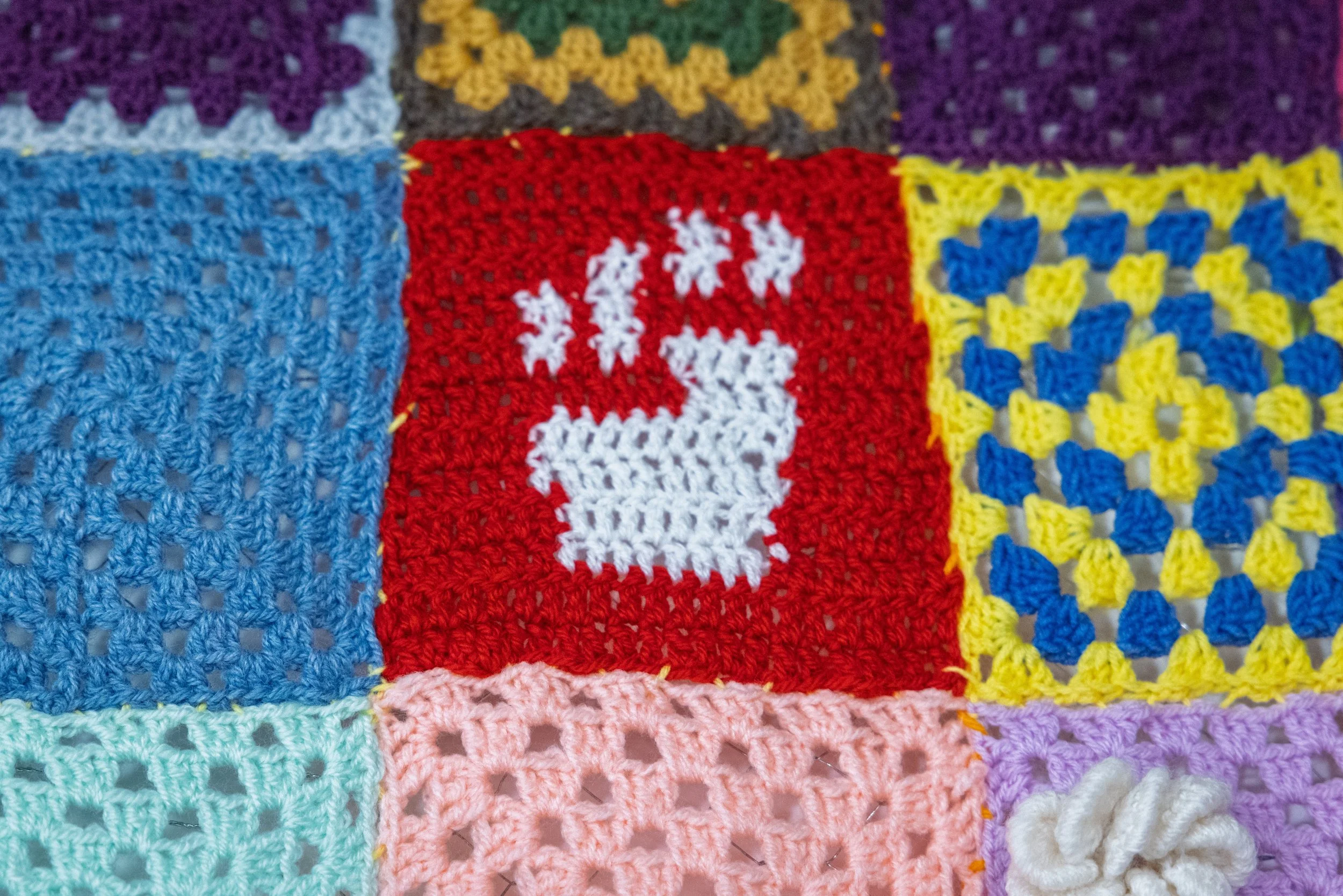 Crocheted white fist on red background
