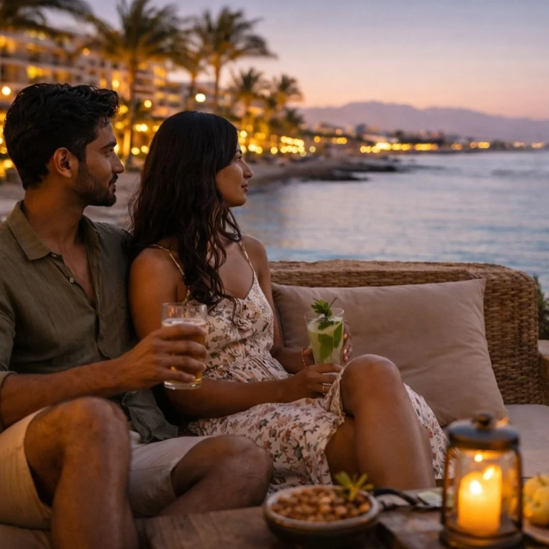 Couple relaxing by the sea at sunset, enjoying drinks at a beachfront resort.