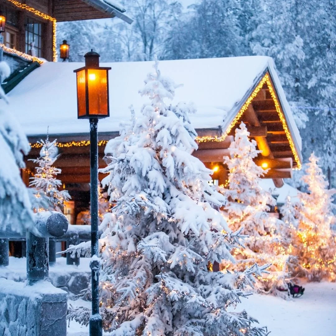 Snow-covered wooden lodge with warm golden lights, frosted pine trees, and a softly lit winter evening setting.