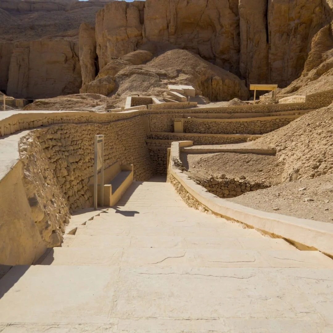 Ancient stone walkways and tomb entrances set against the desert cliffs of the Valley of the Kings.
