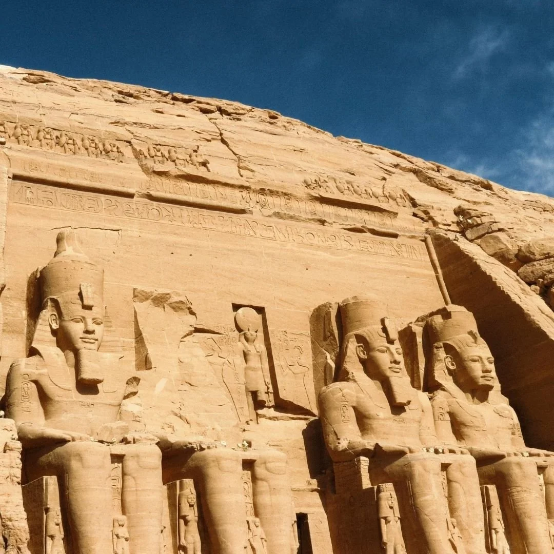 Ancient rock-cut temple statues in Egypt, carved into sandstone cliffs, captured in natural light without crowds.