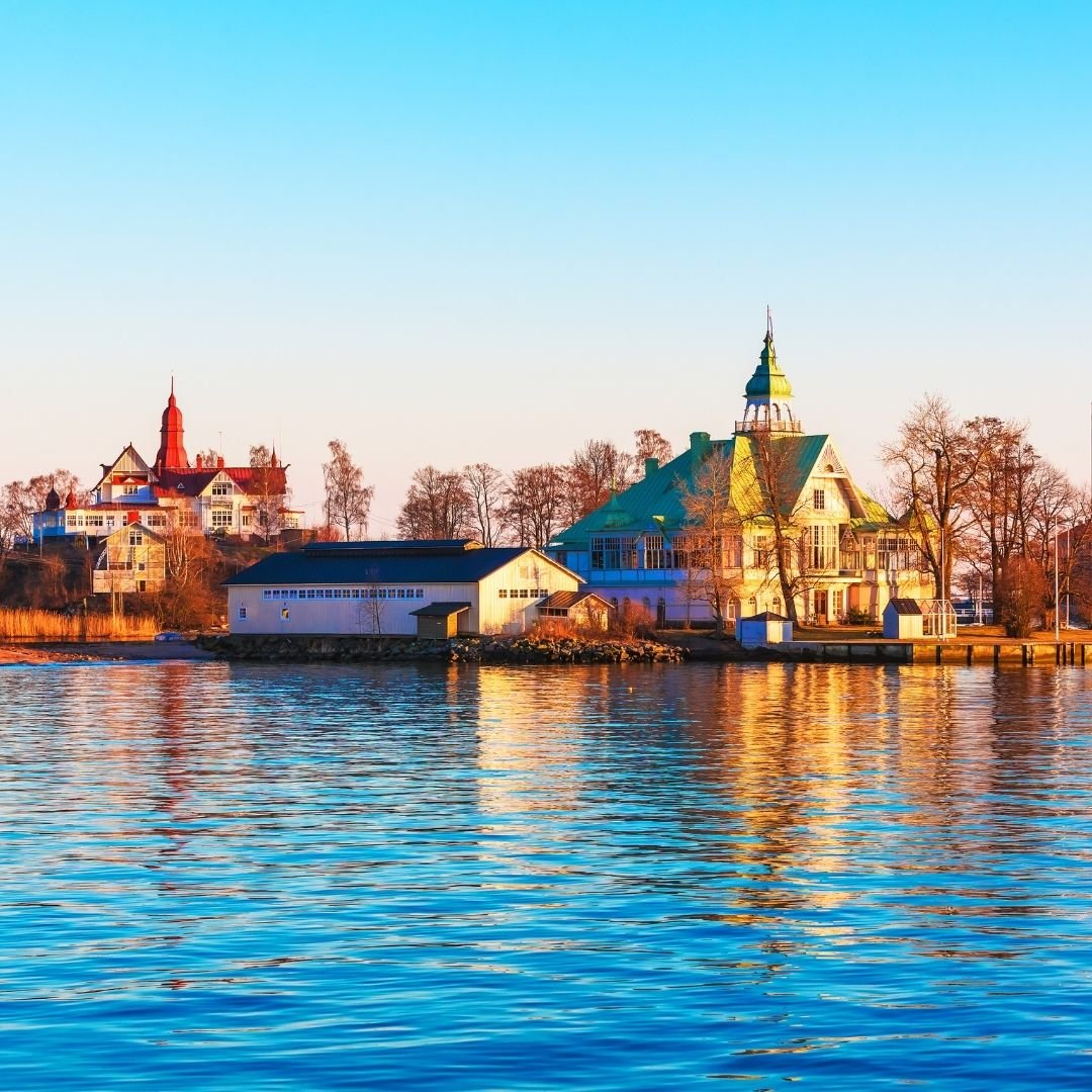 Historic waterfront buildings in Helsinki reflecting softly on calm blue water under a clear sky.