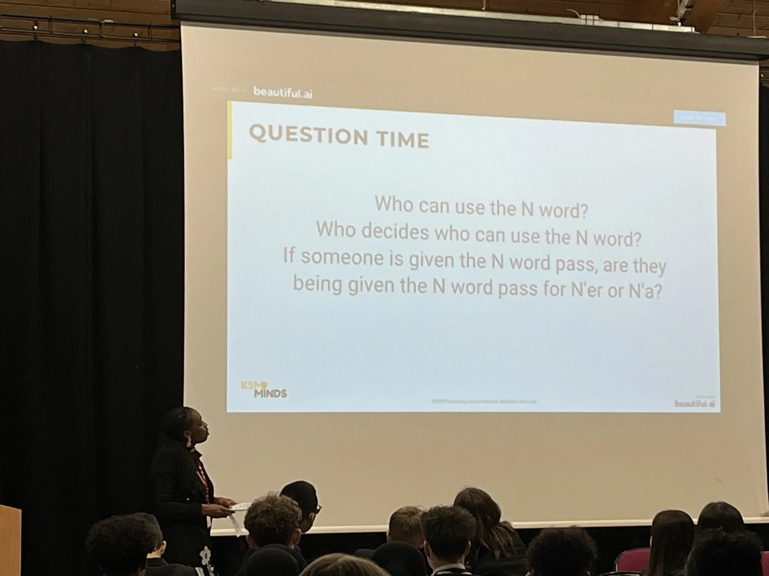 A woman giving a presentation to an audience, with a slide titled 'Question Time' that asks about the use and decision-making process surrounding the letter 'N' in words.