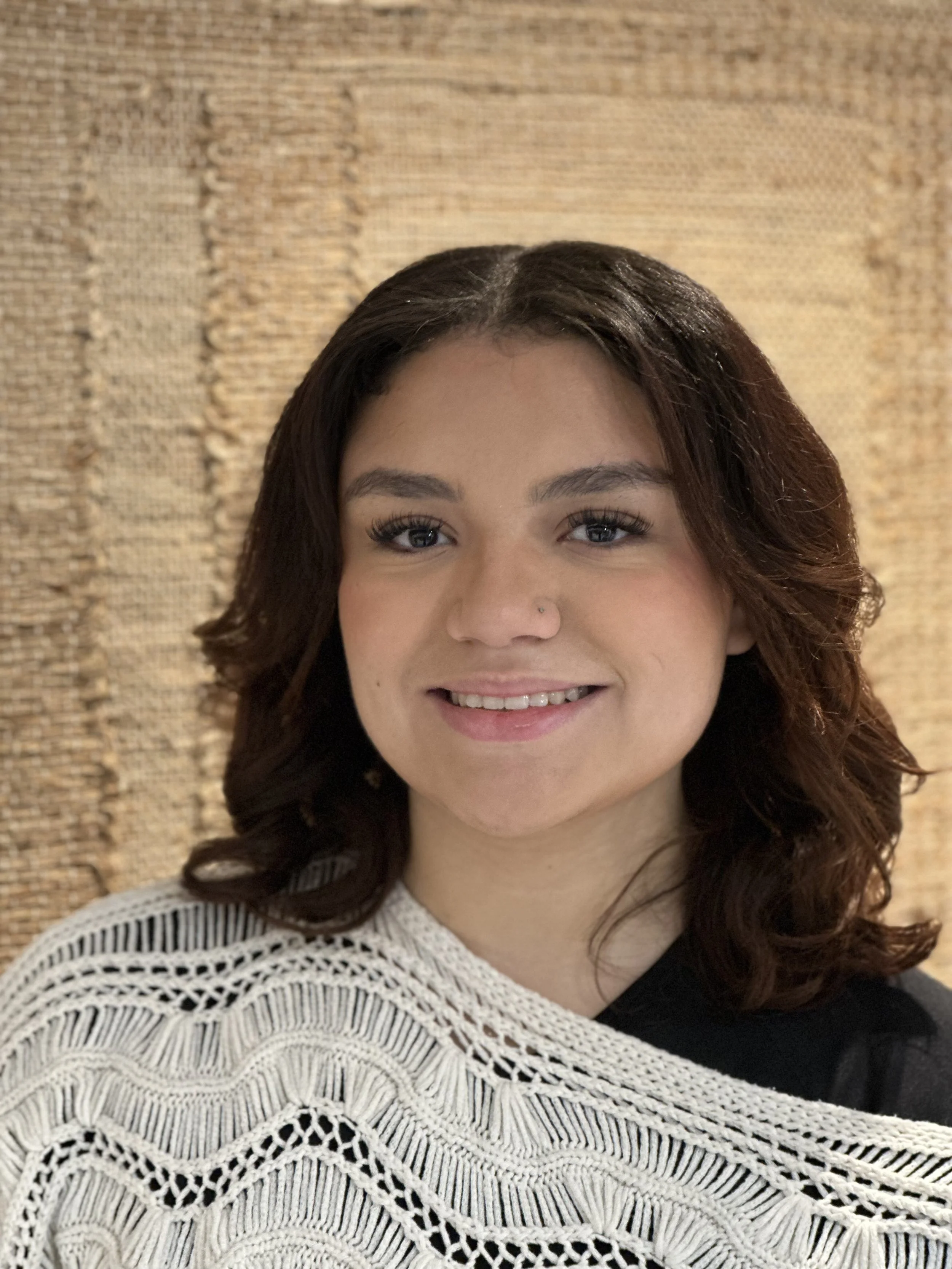 Sofia a trainee stylist at butchers hair salon checter in front of a beige wall hanging