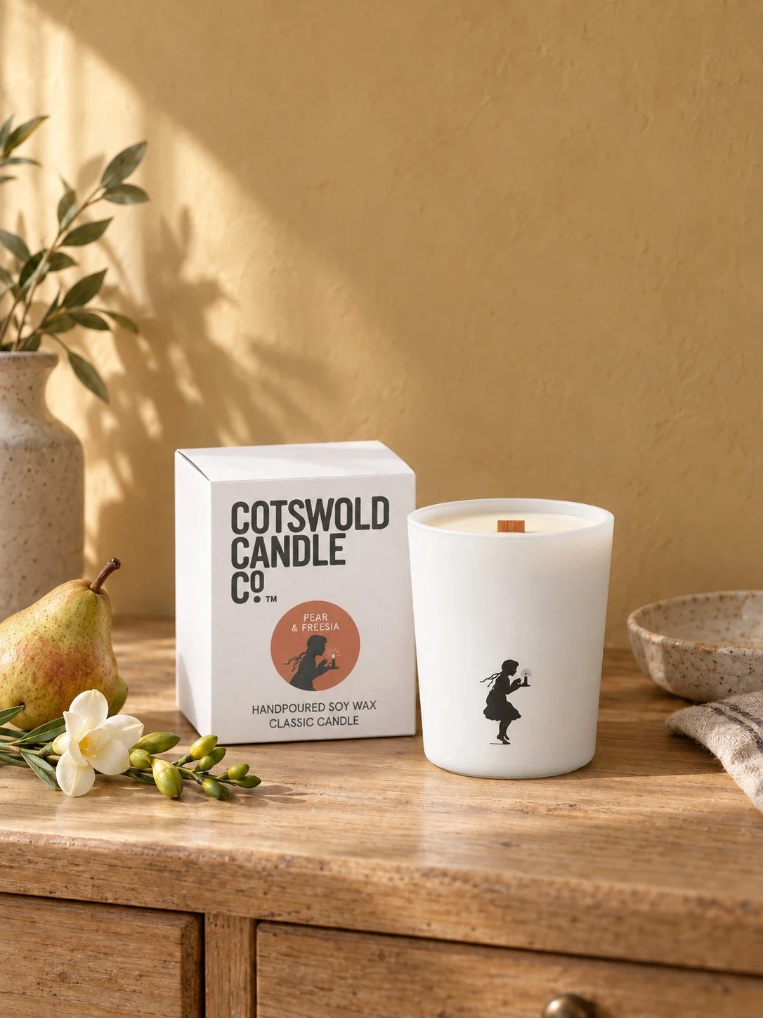 Pear & Freesia wood wick candle and matching box by Cotswold Candle Co., styled in a home interior with natural light.