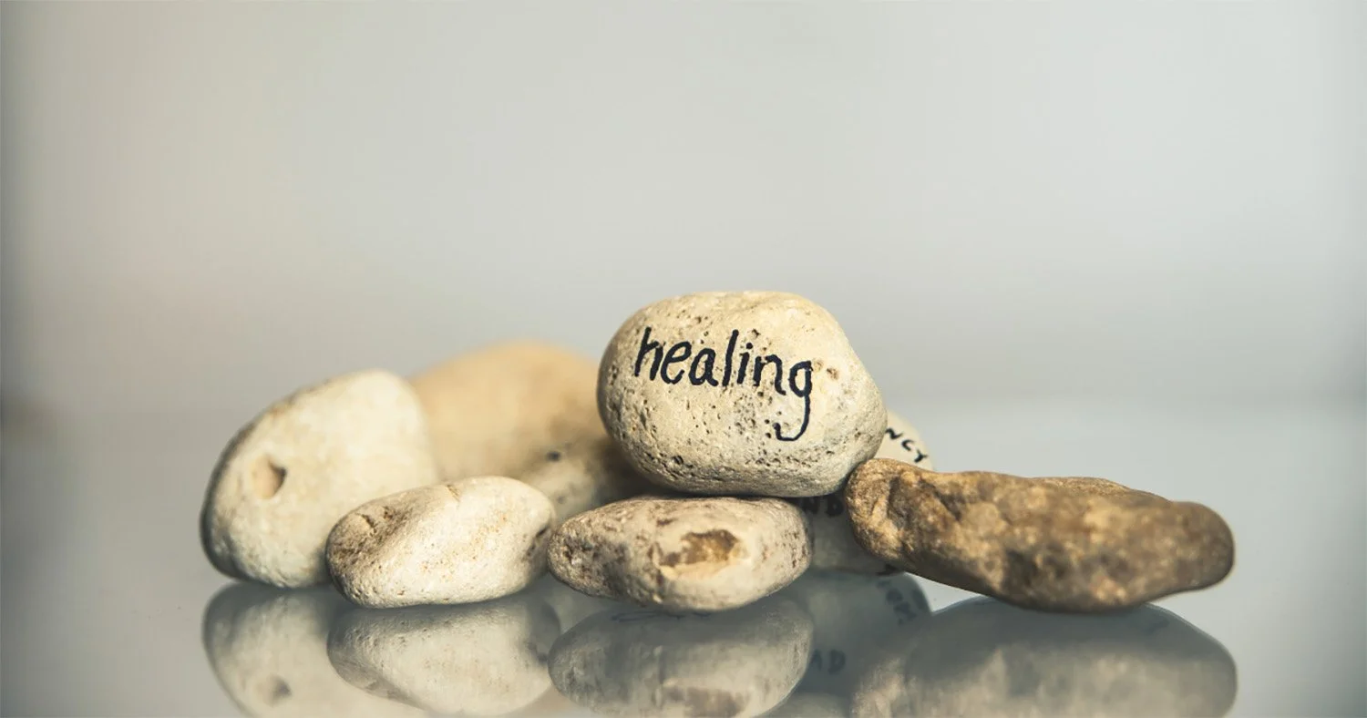 Assortment of rock with the top rock inscribed with the word healing - New Pathways Therapy