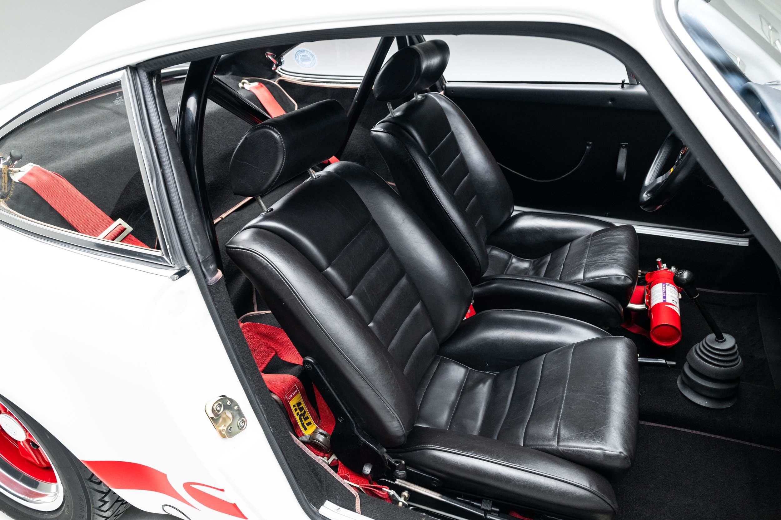Black leather seats, red harnesses, and a fire extinguisher inside the 1973 Porsche 911 Carrera RS.