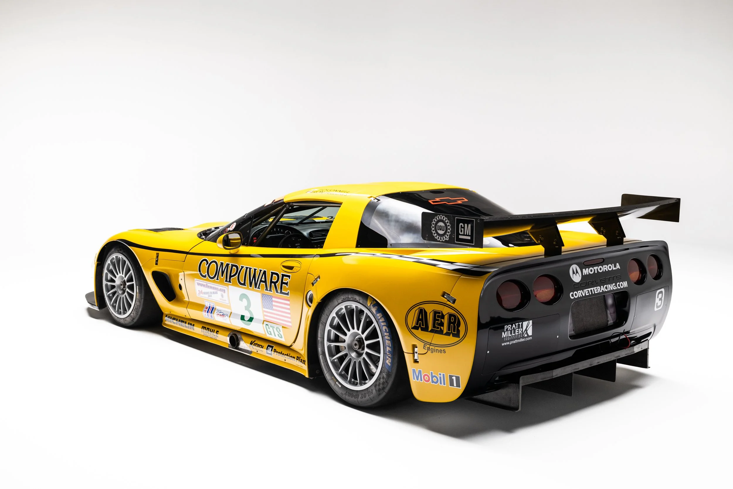 Rear three-quarter studio view of the yellow number 3 Corvette C5-R, showing its Compuware livery and large rear wing.