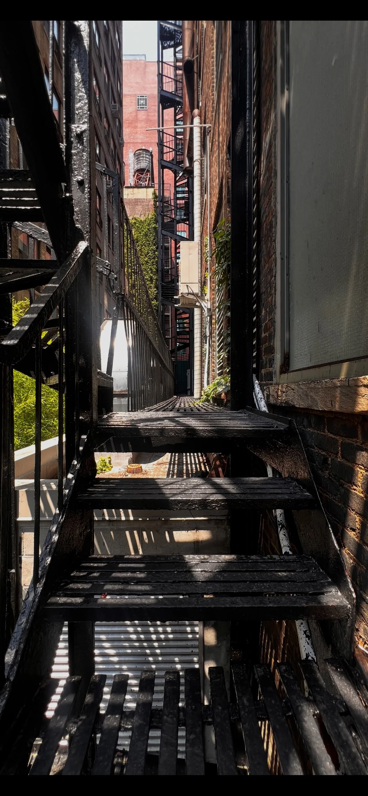 Metal grate landing on fire escape staircase, urban alley view