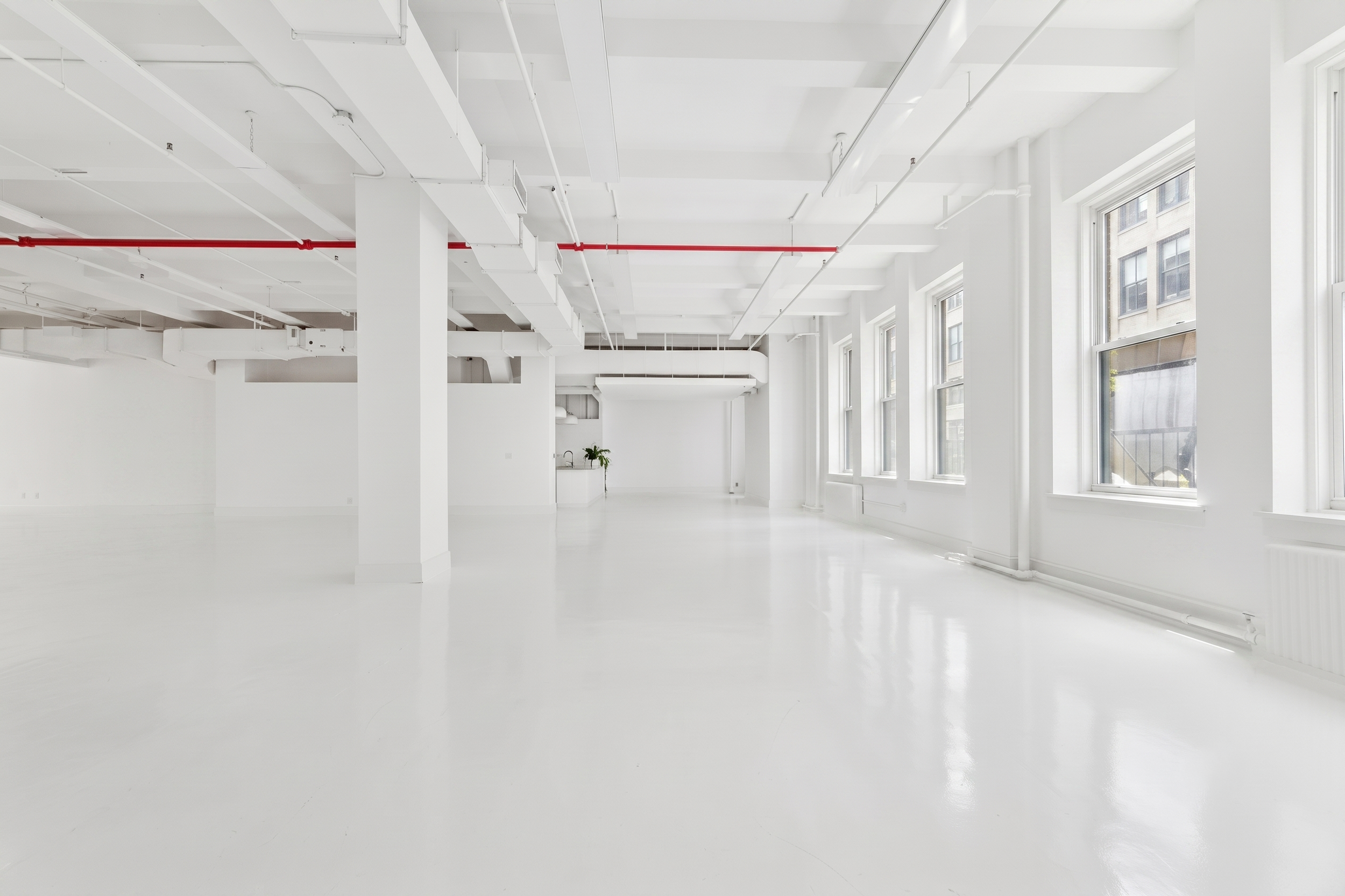 Empty white loft studio with tall windows and red exposed pipe, glossy white floor