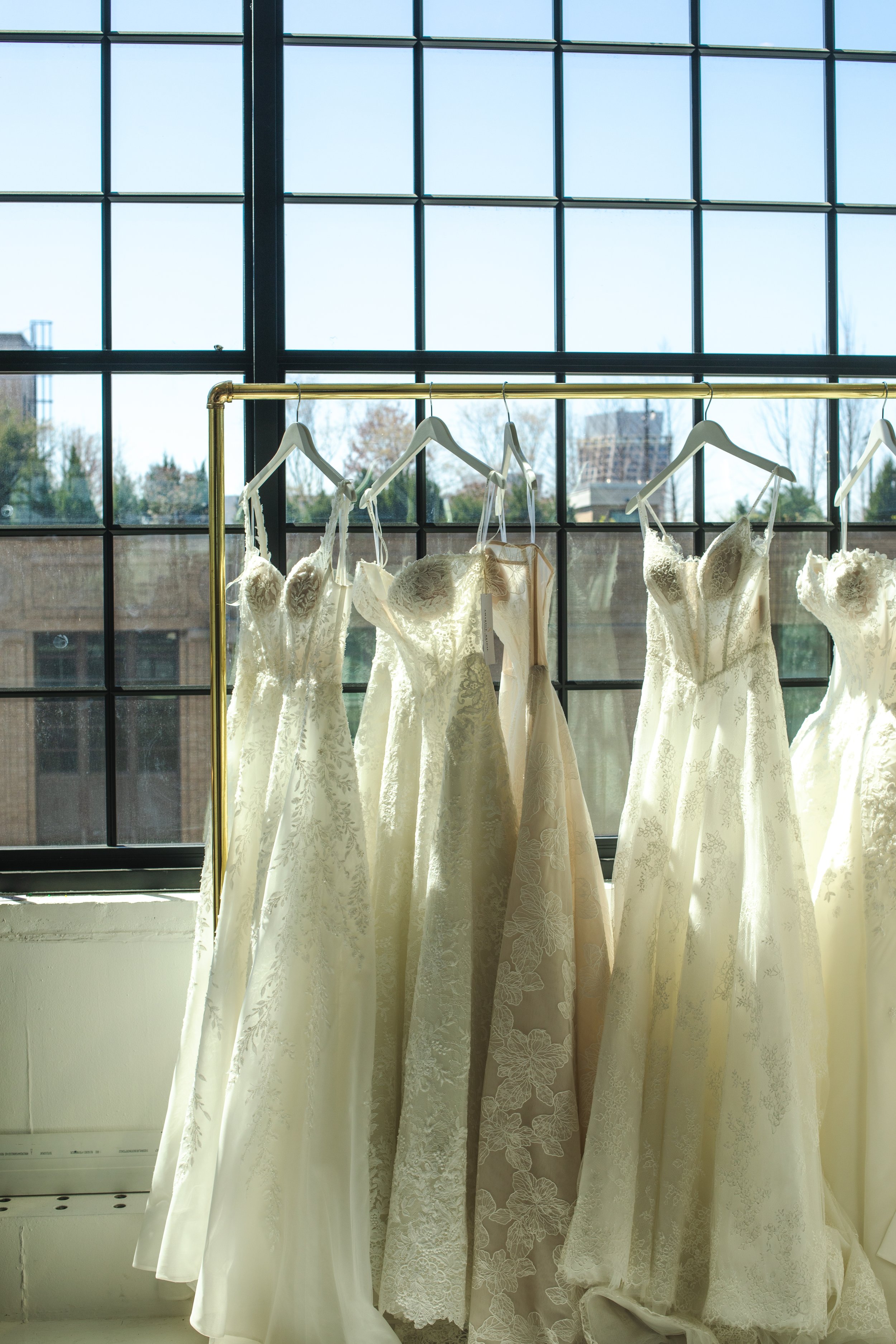 Row of ivory and champagne lace wedding gowns on a wardrobe rack at Daylight Studio's Hudson Yards bridal showroom venue in NYC.