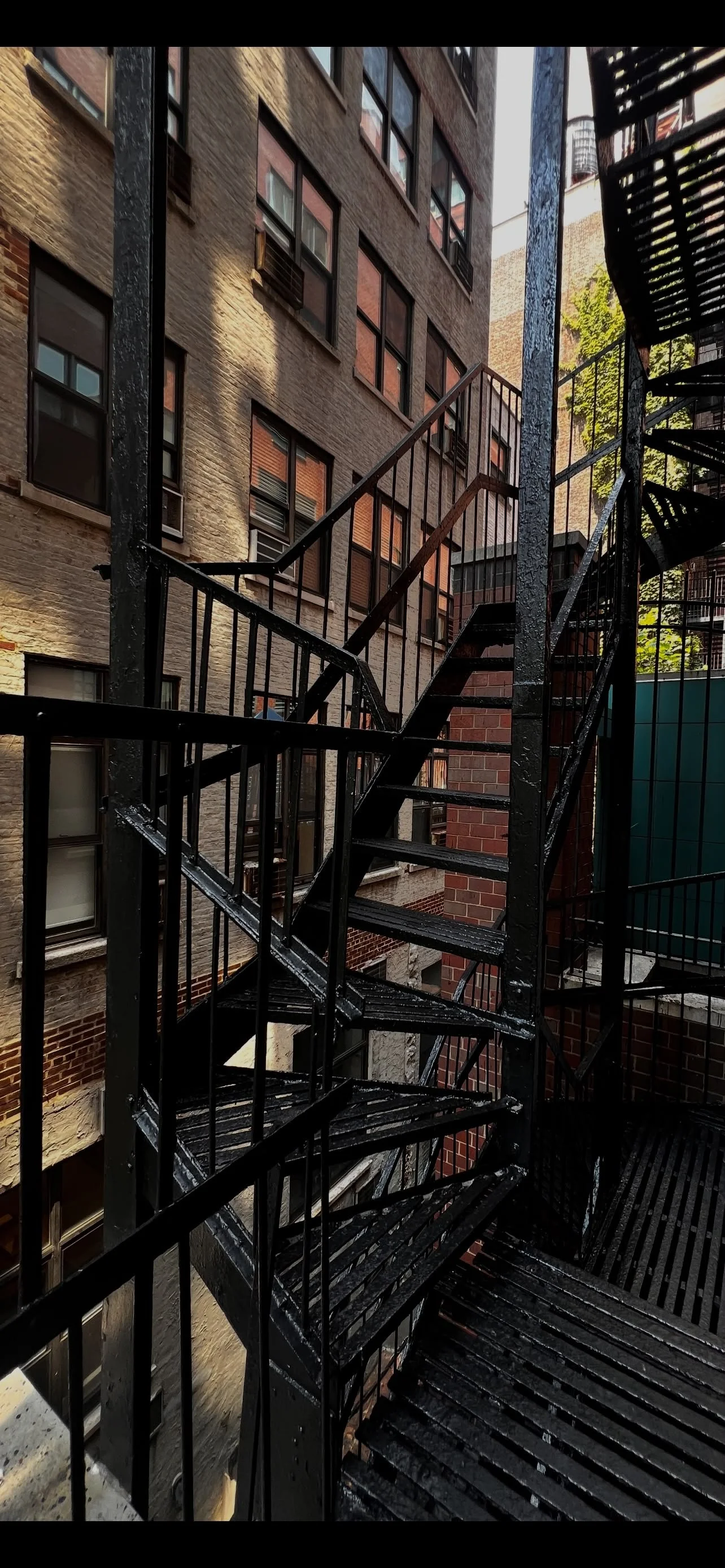 Iron spiral fire escape staircase between city apartment buildings