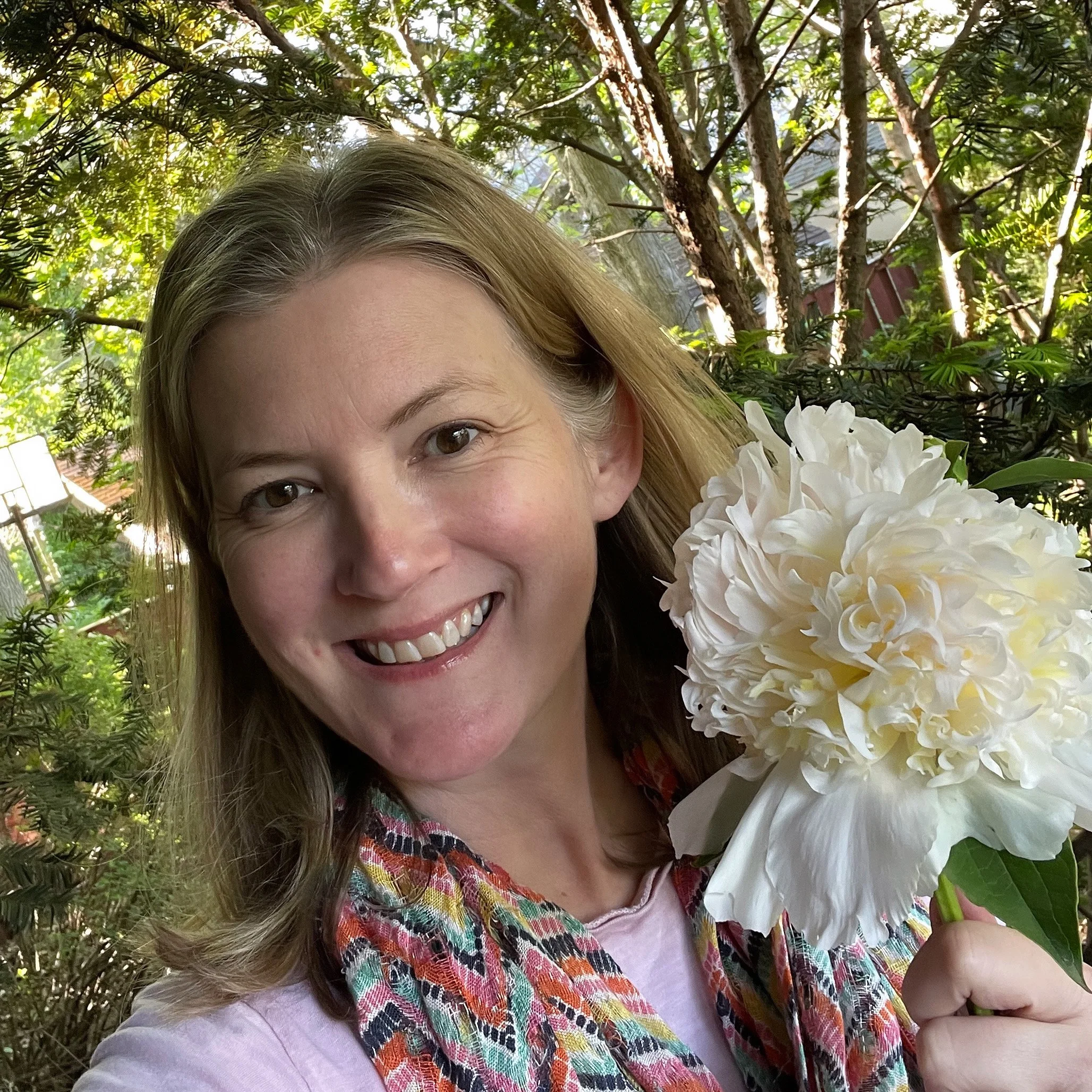 photo of smiling white woman holding a light yellow peony