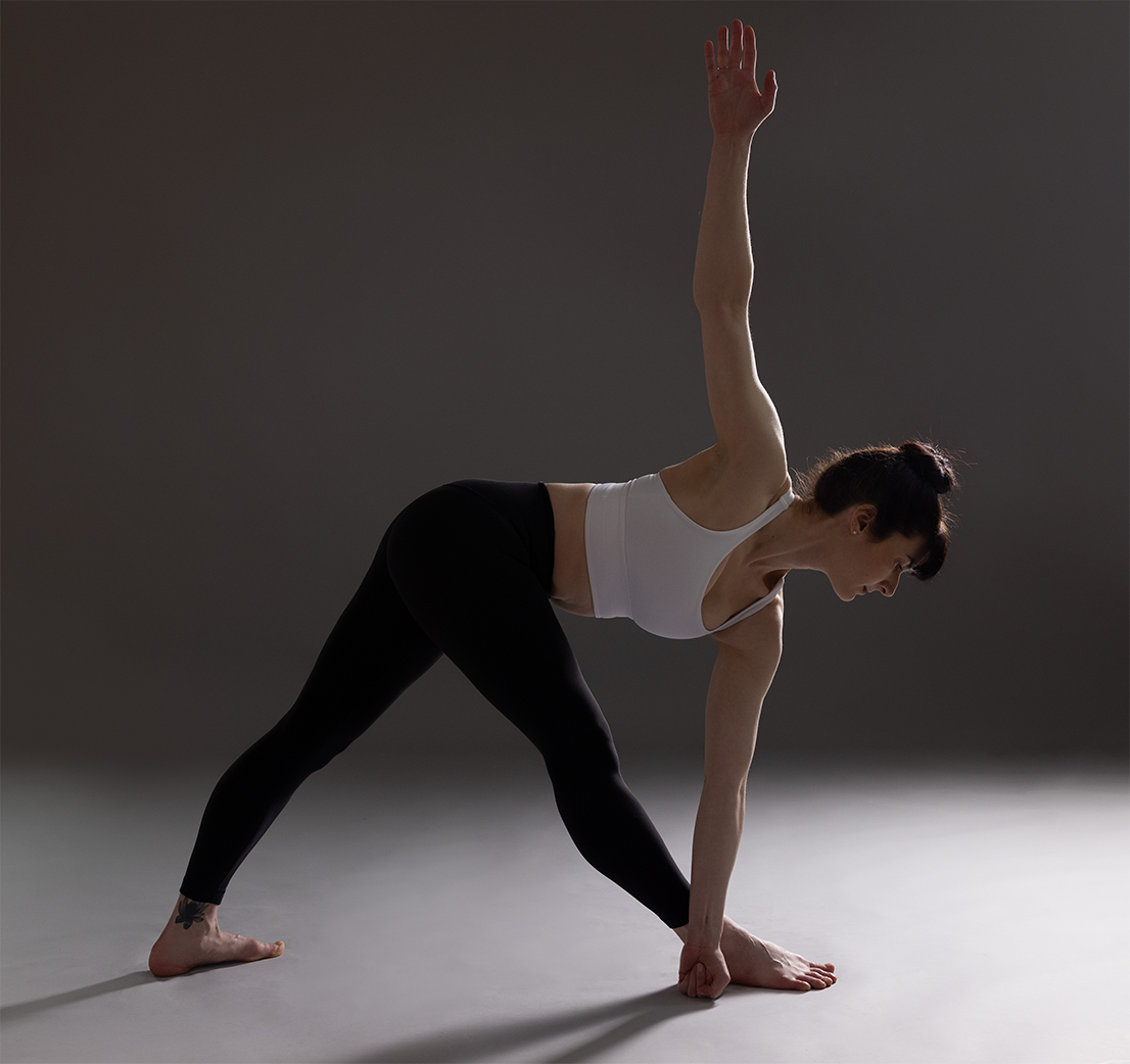Elizabeth Voetsch in Parivrtta Trikonasana (Revolved Triangle Pose); view the schedule for group yoga classes in Kingston, NY and Hudson, NY, private yoga sessions, online and on-deman yoga and pilates classes, and yoga workshops.