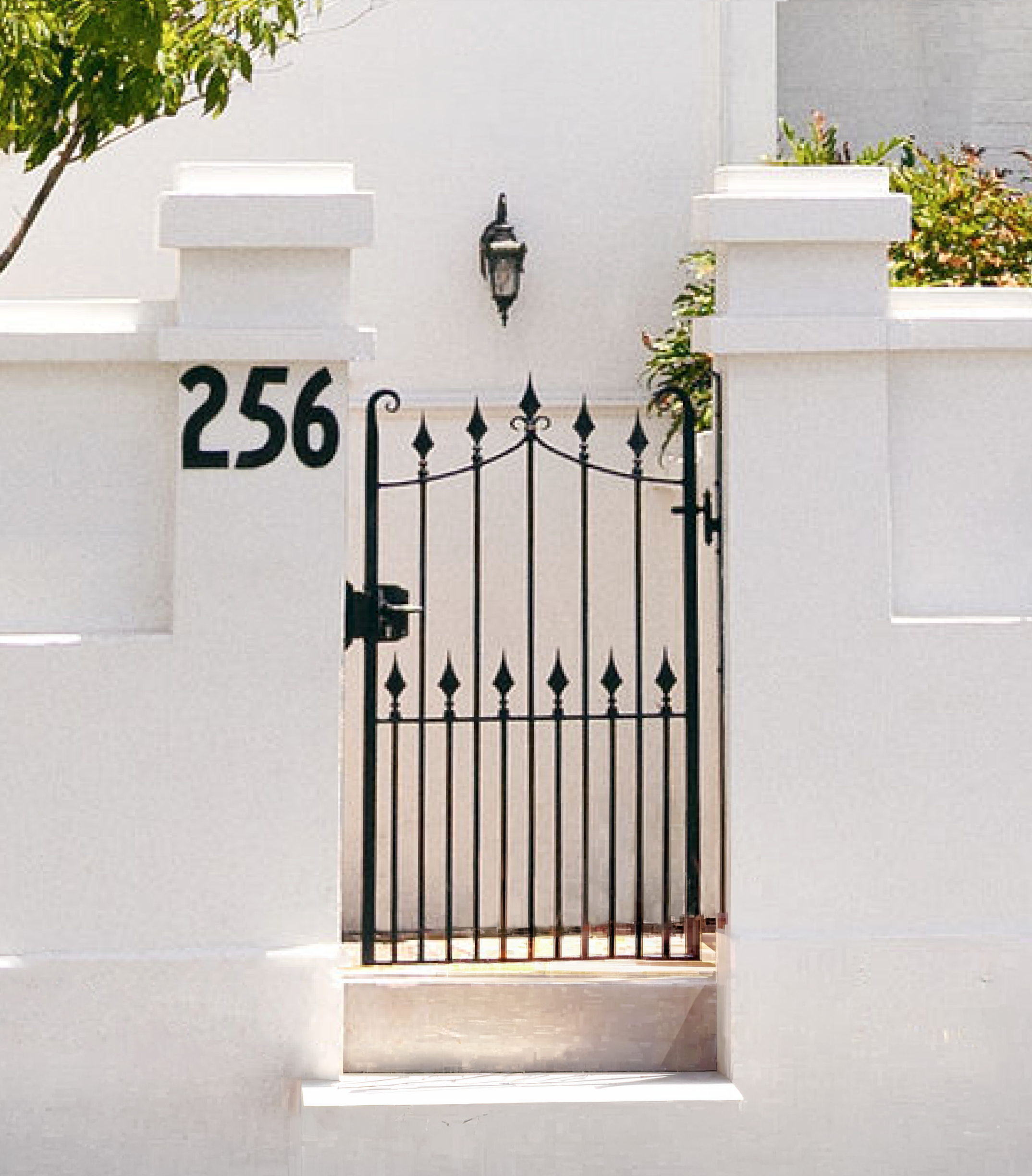 Front exterior of The Manor Clinic Brisbane, showcasing heritage-listed Victorian architecture with black cast iron gate number 256, detailed balcony, greenery, and grand entrance.