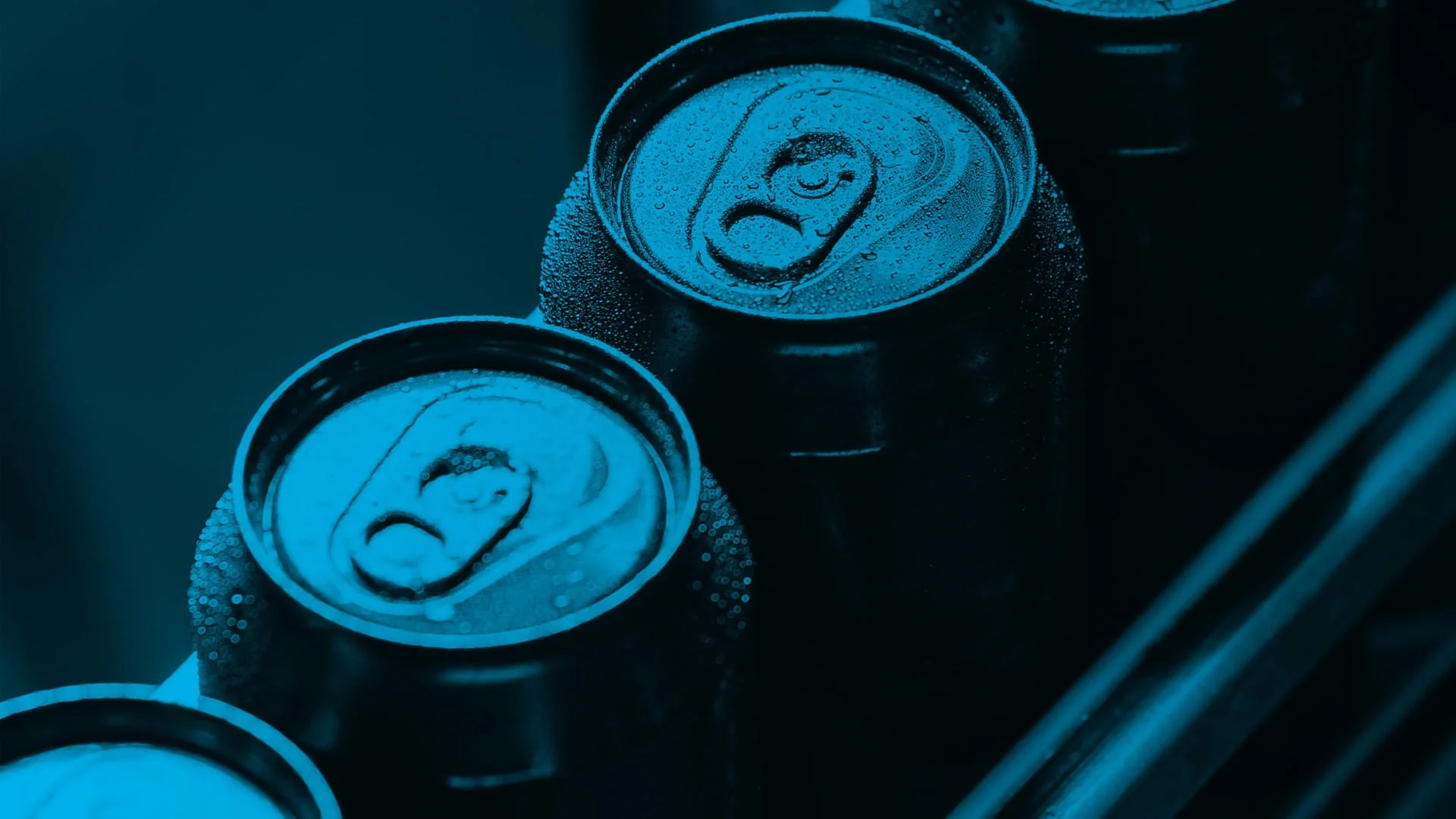 Close-up of soda cans in a cooler, covered in condensation with a blue tint.