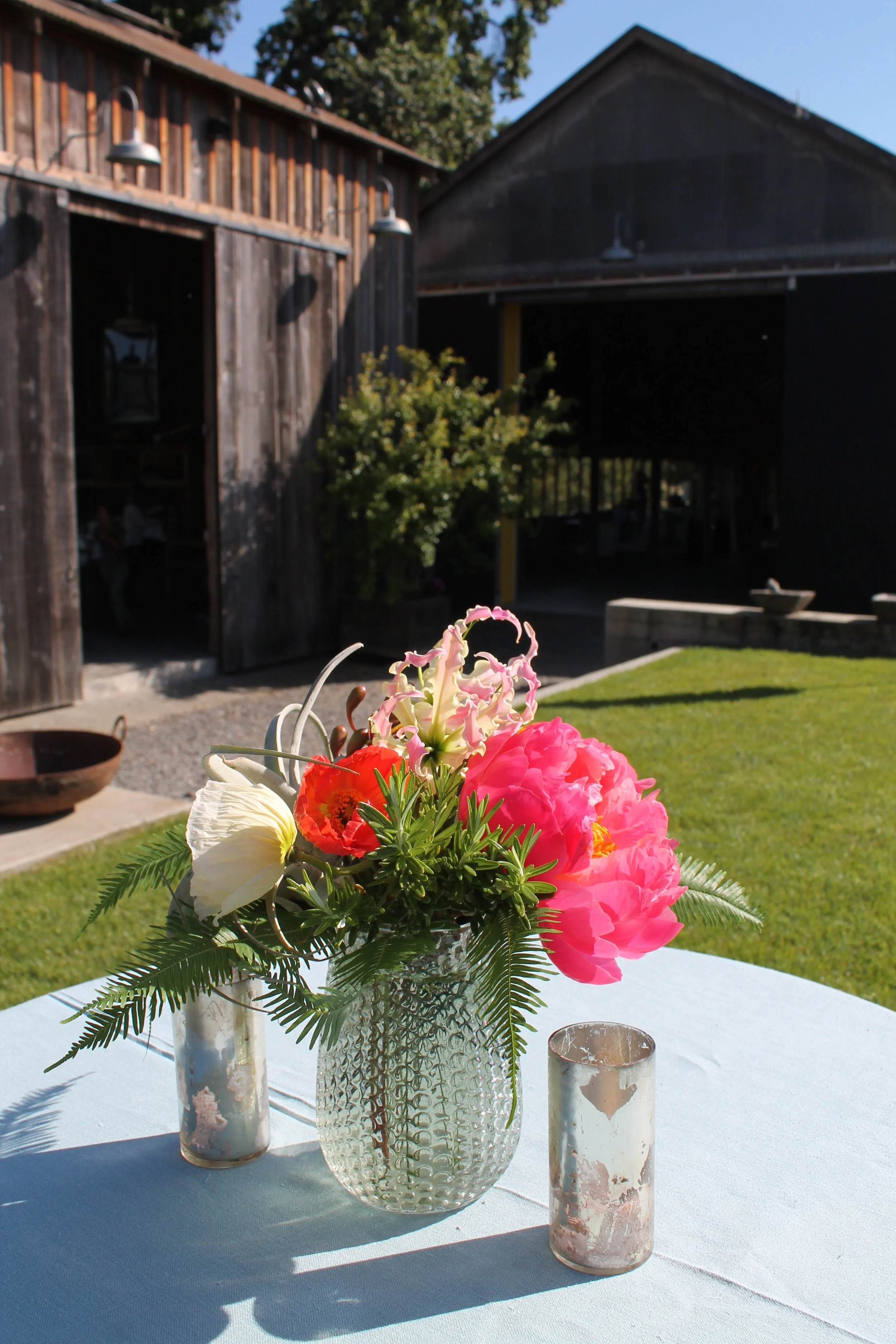 bright pink coral flowers in vase with metal votives