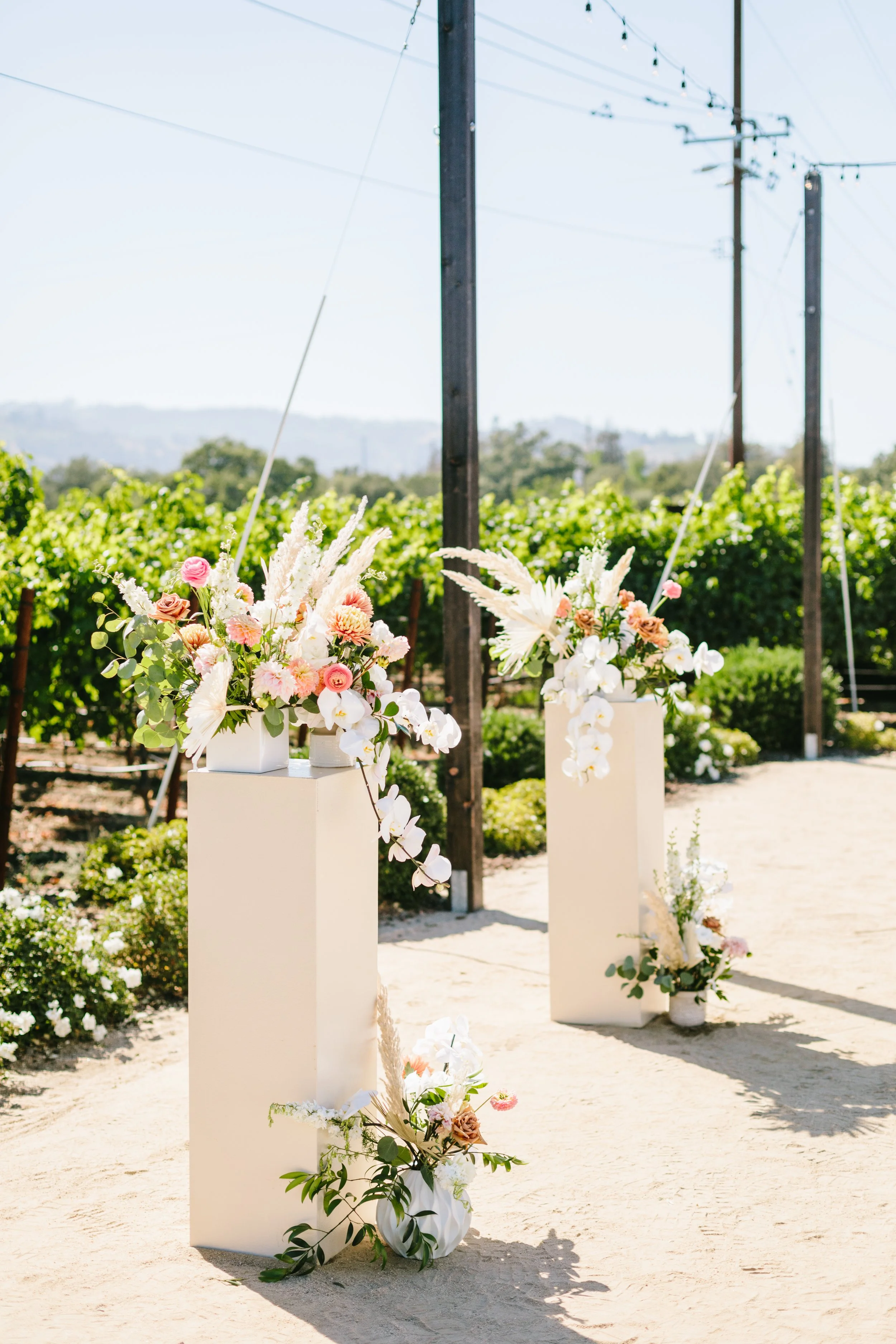 Foral arrangements sit on a pillar in front of California vineyard. Image name: wedding-florist-boise-157
