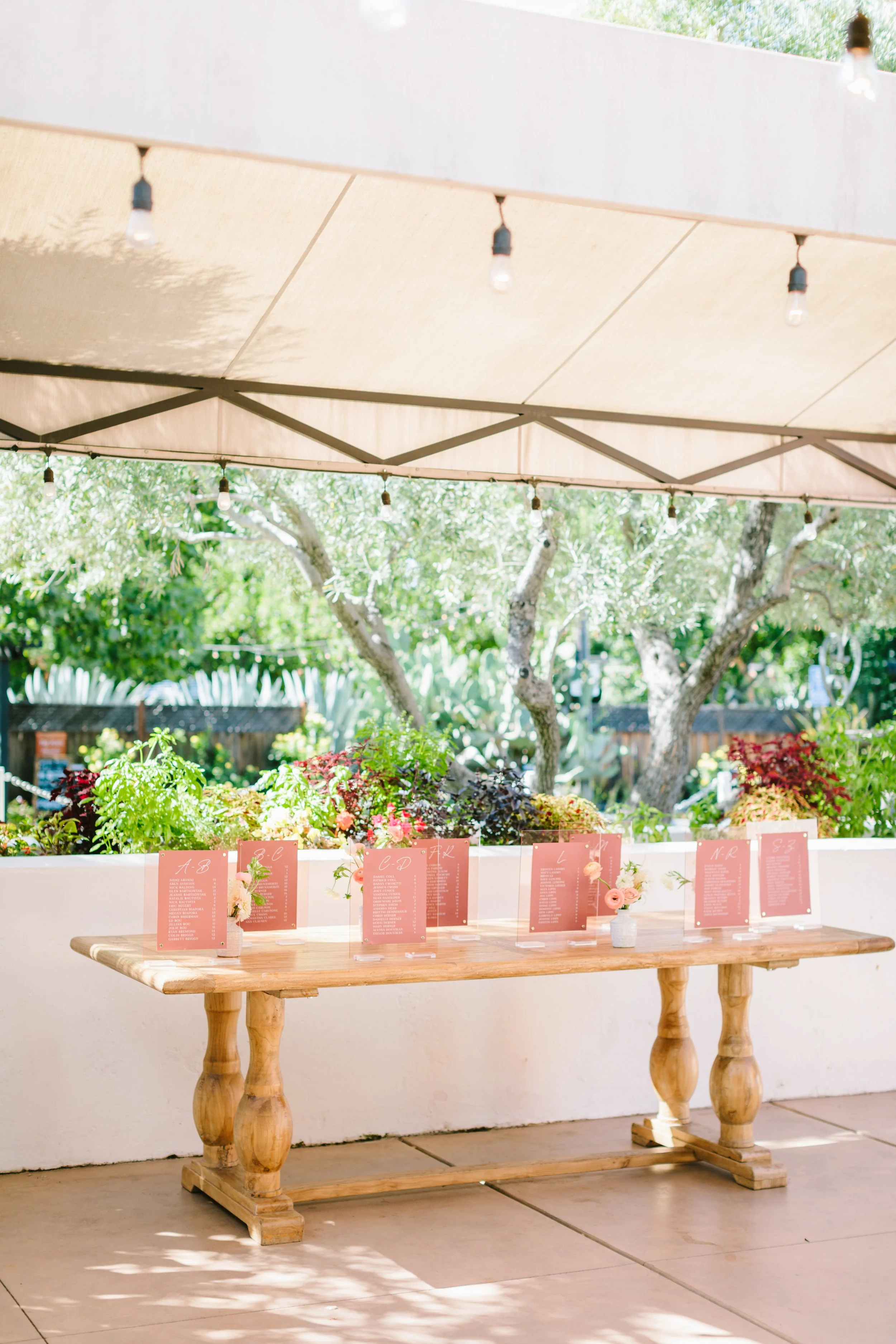 Pink acrylic table sitting cards with pink ranunculus in small vases. Image name: wedding-florist-boise-164