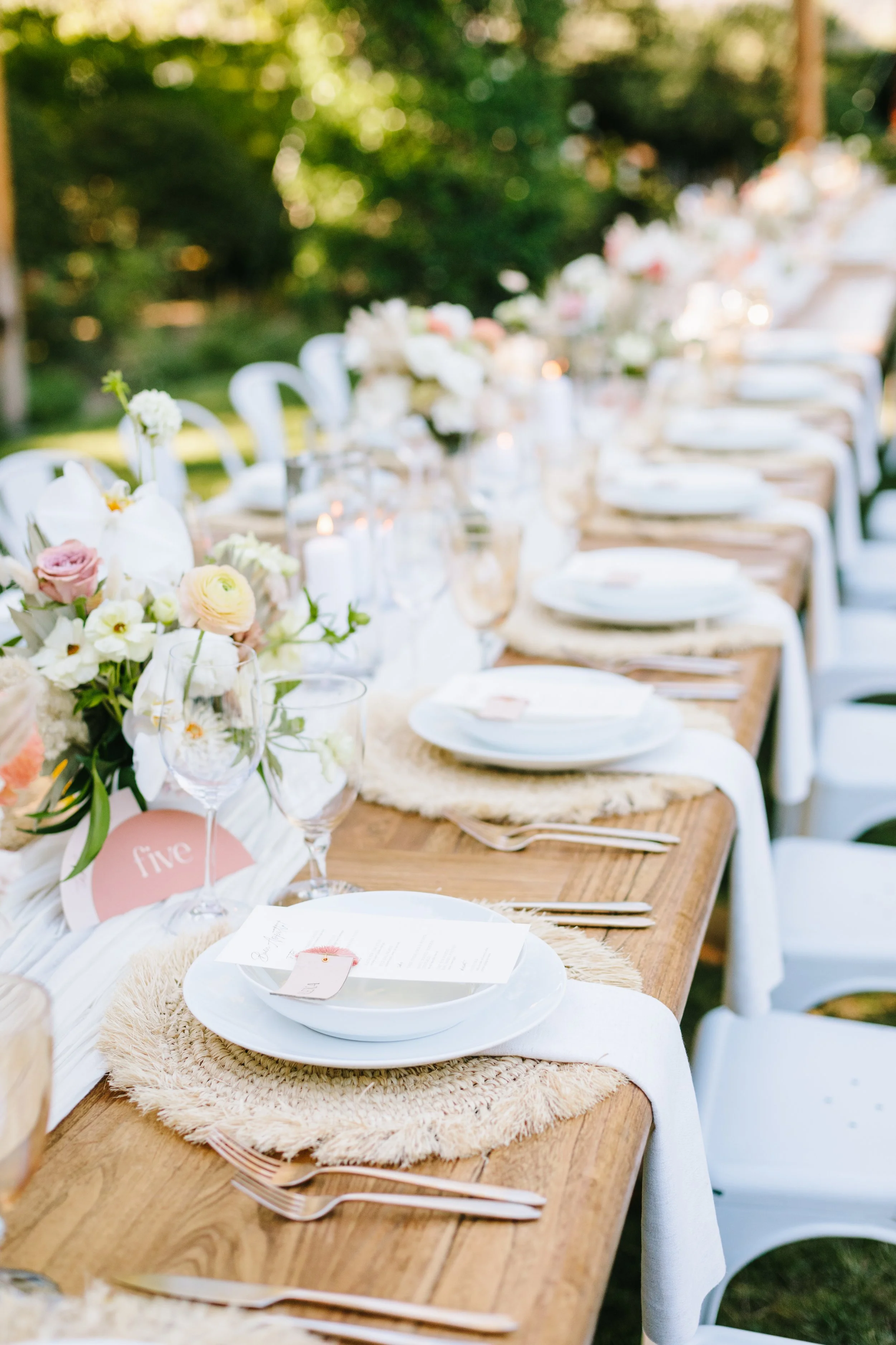 Tables with vases of pink ranunculus, pink roses, white roses, dahlias. Image name: wedding-florist-boise-169