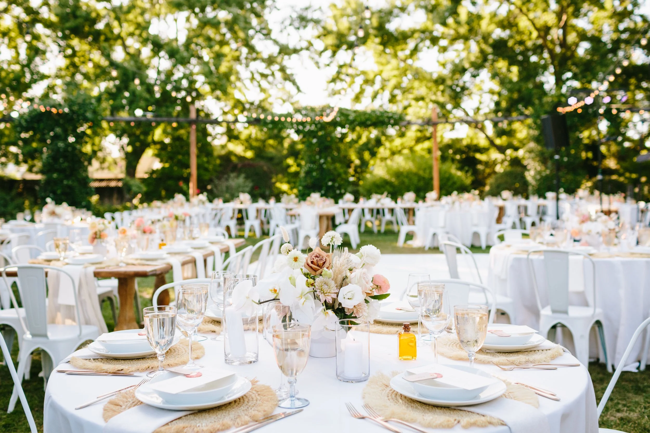Tables with white vases filled with pink ranunculus, pink roses, white roses, dahlias. Image name: wedding-florist-boise-168