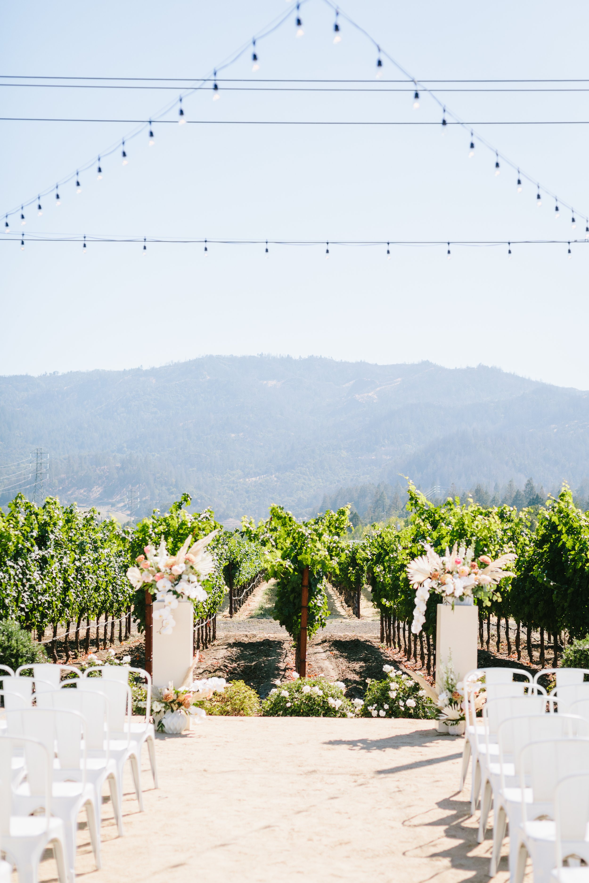 Pillars of white roses, white orchids, white hydrangeas, pink ranunculus, white dahlias. Image name: wedding-florist-boise-154