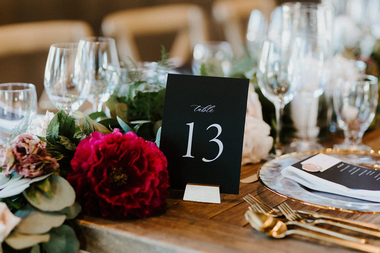 Red peony next to table number wine glasses image name: wedding-florist-boise-202