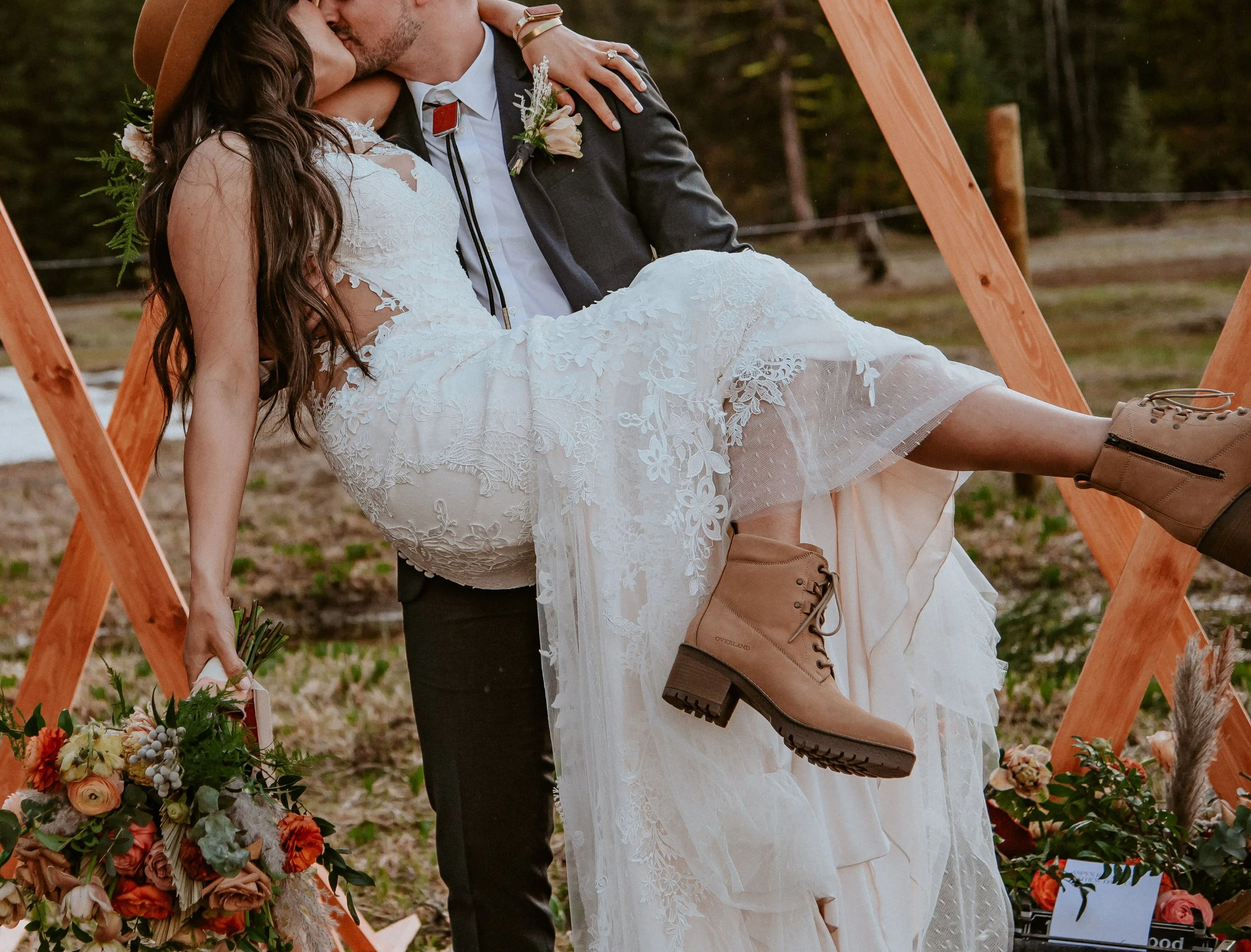 Husband holds his bride her bouquet roses, ranunculus, wildflowers. Image name: wedding-florist-boise-108