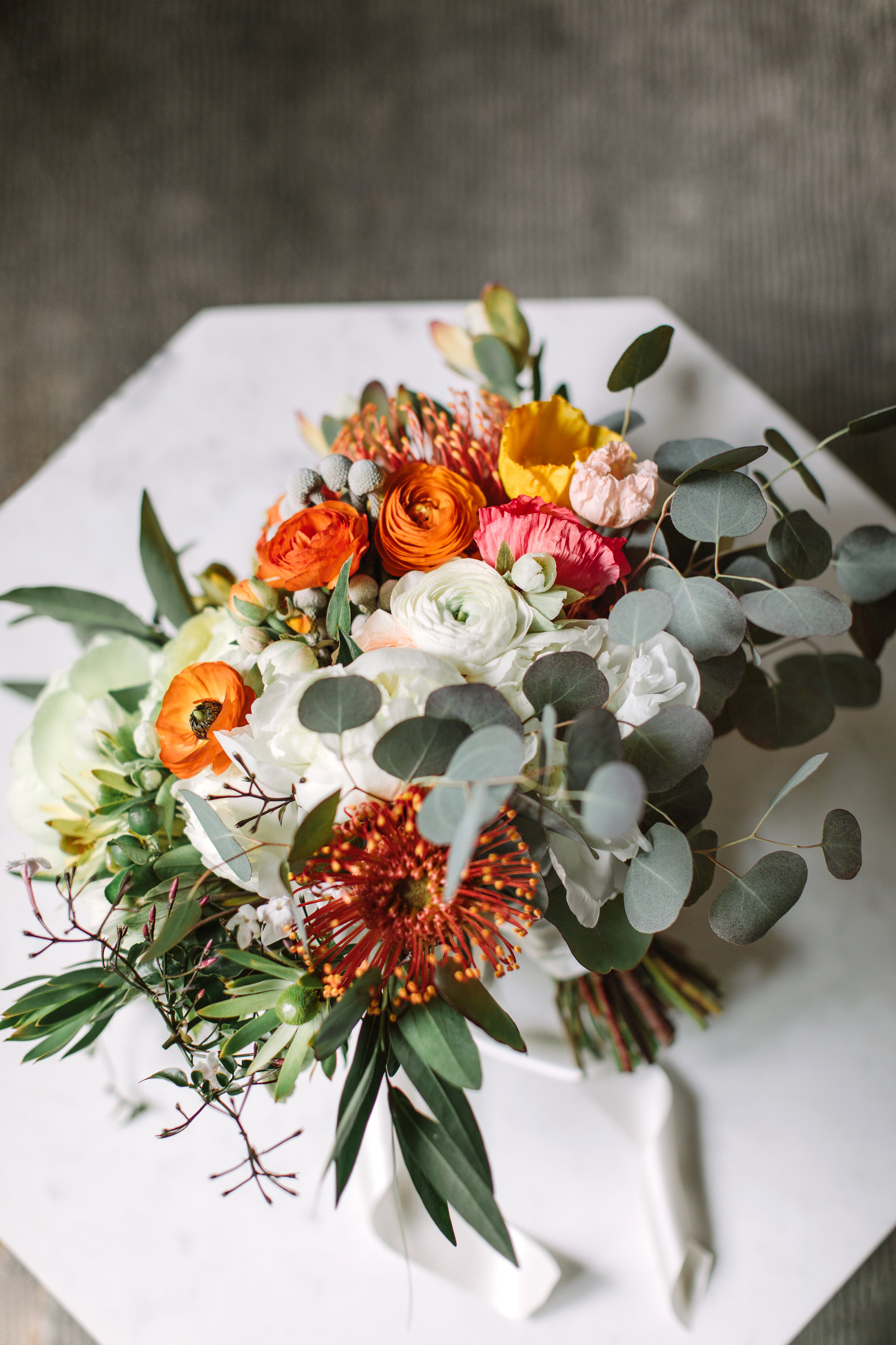 Bouqet with protea white roses yellow poppies orange poppies eucalyptus leaves image name: wedding-florist-boise-785