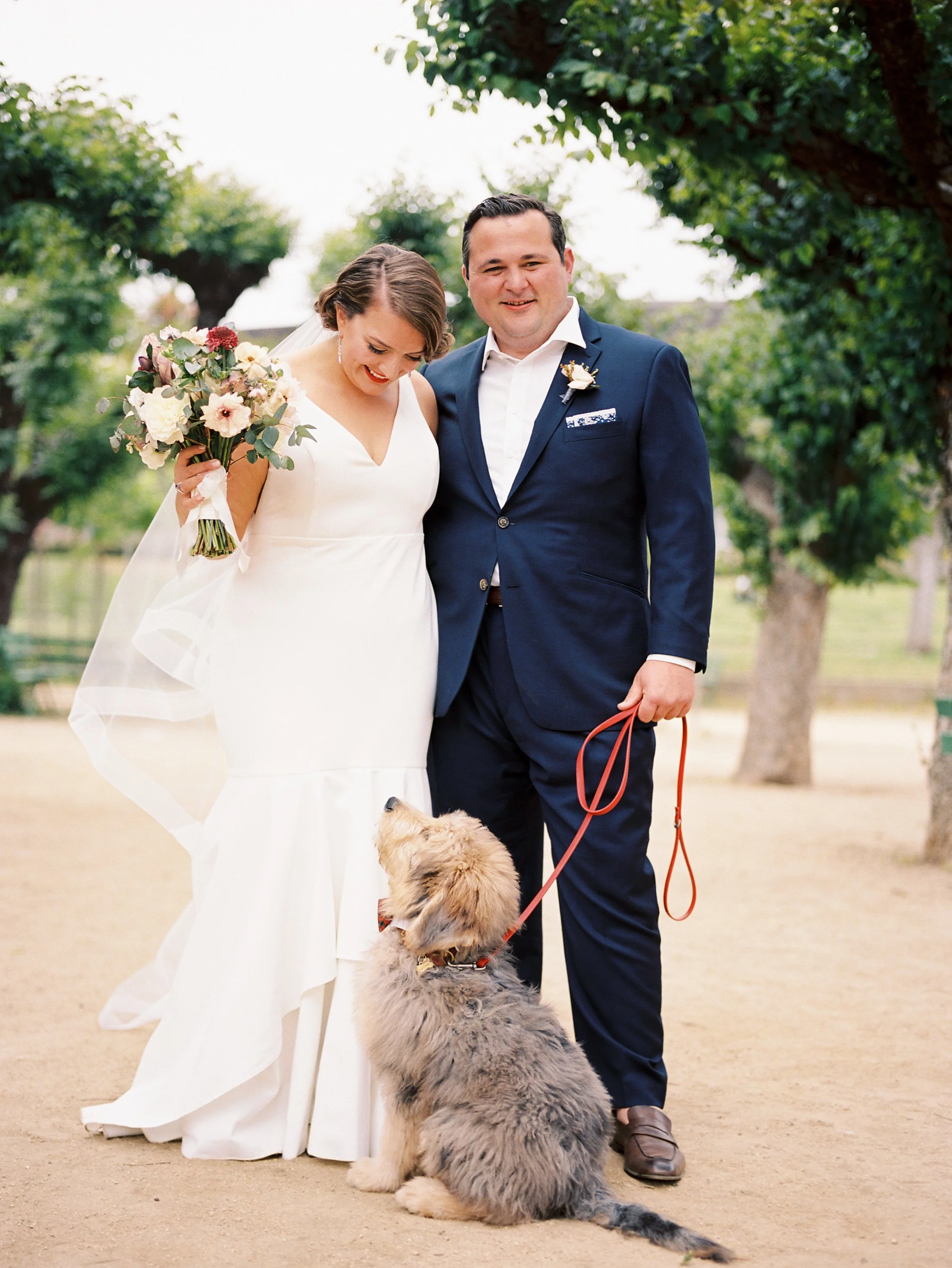 Bride holding bouquet of anemone, peonies, white roses with dog and groom image name: wedding-florist-boise-400