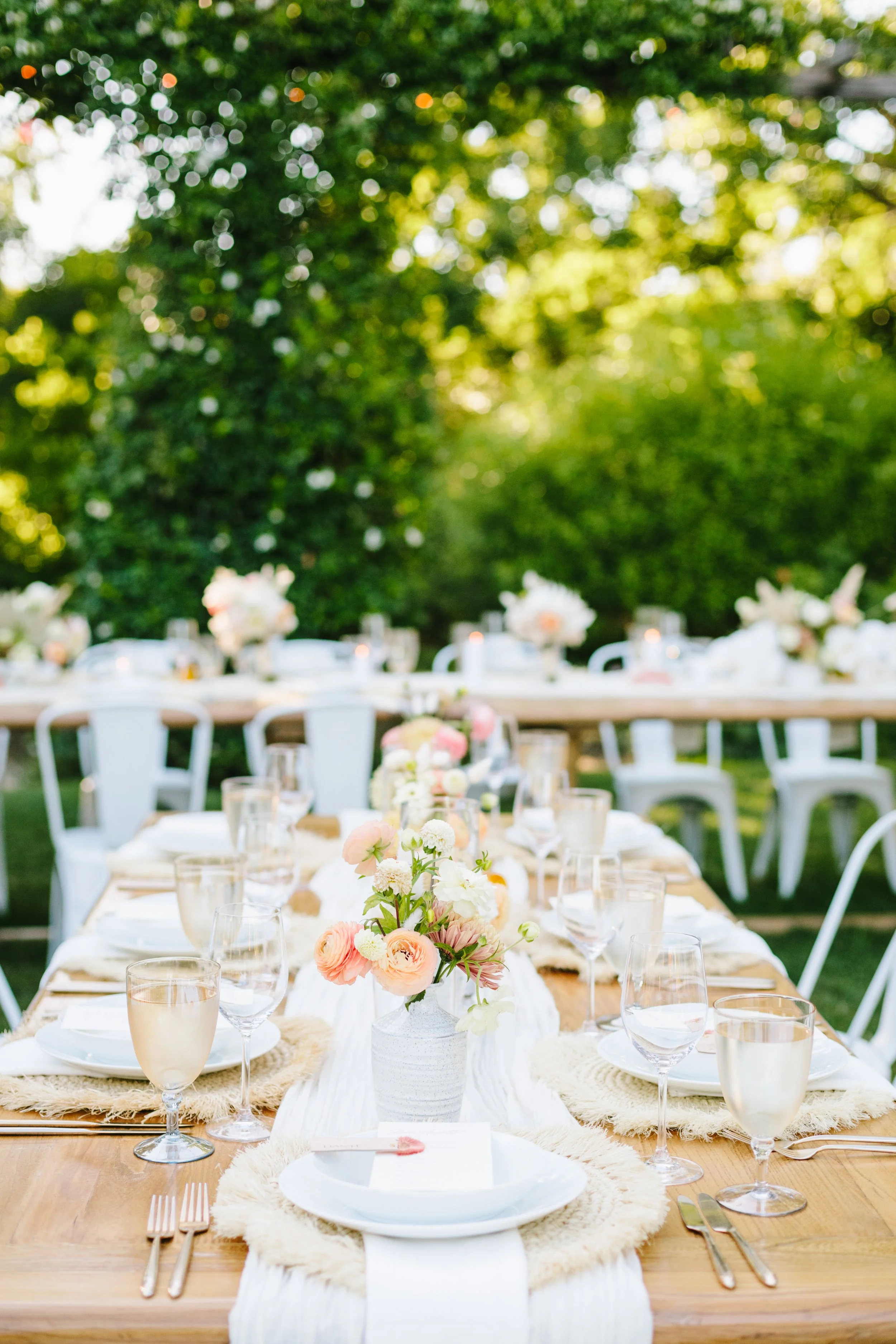 Tables with white vases filled with pink ranunculus. Image name: wedding-florist-boise-167