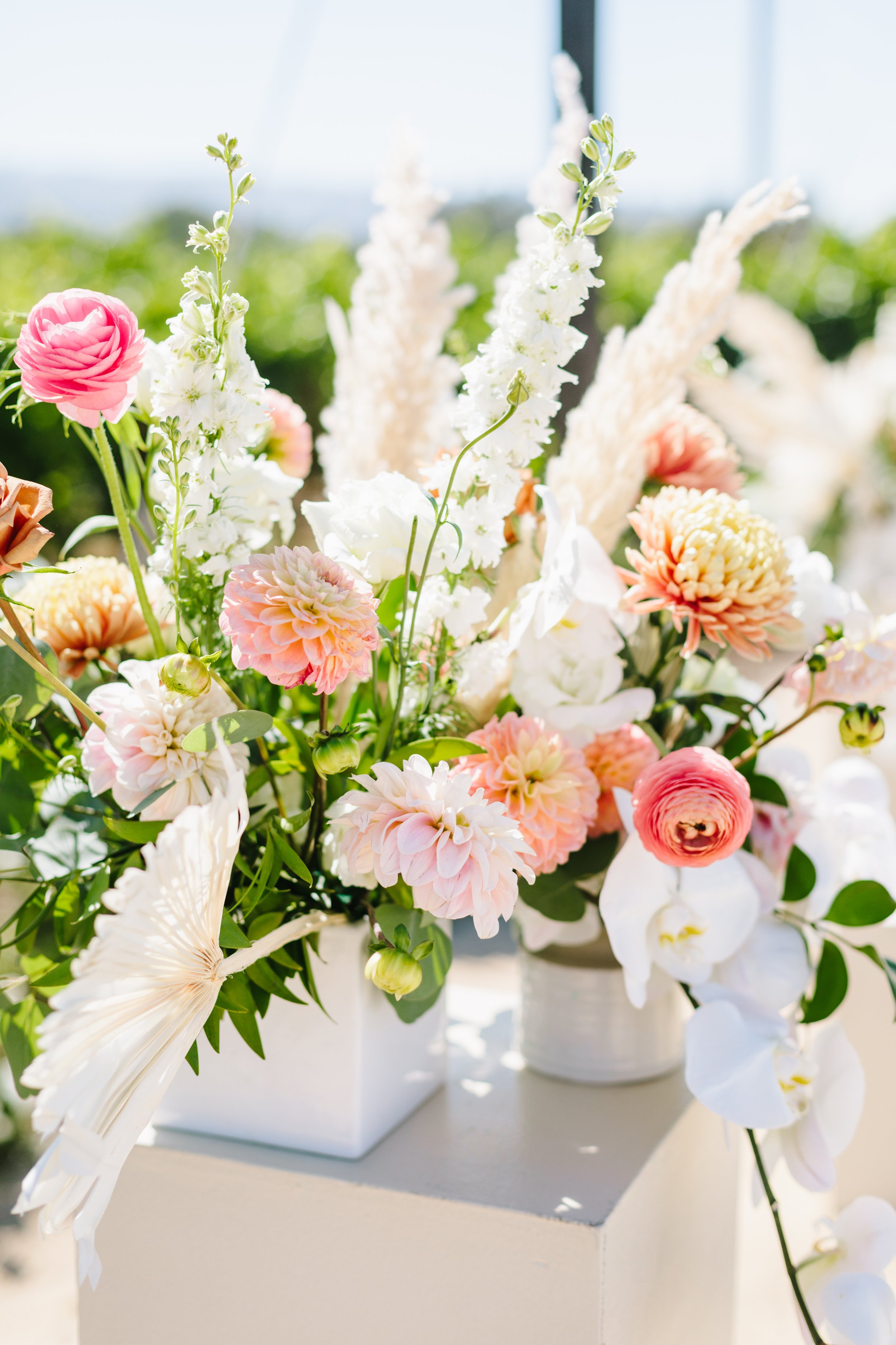 Pink ranunculus, white orchids,  pink dahlias make up a floral arrangement. Image name: wedding-florist-boise-158