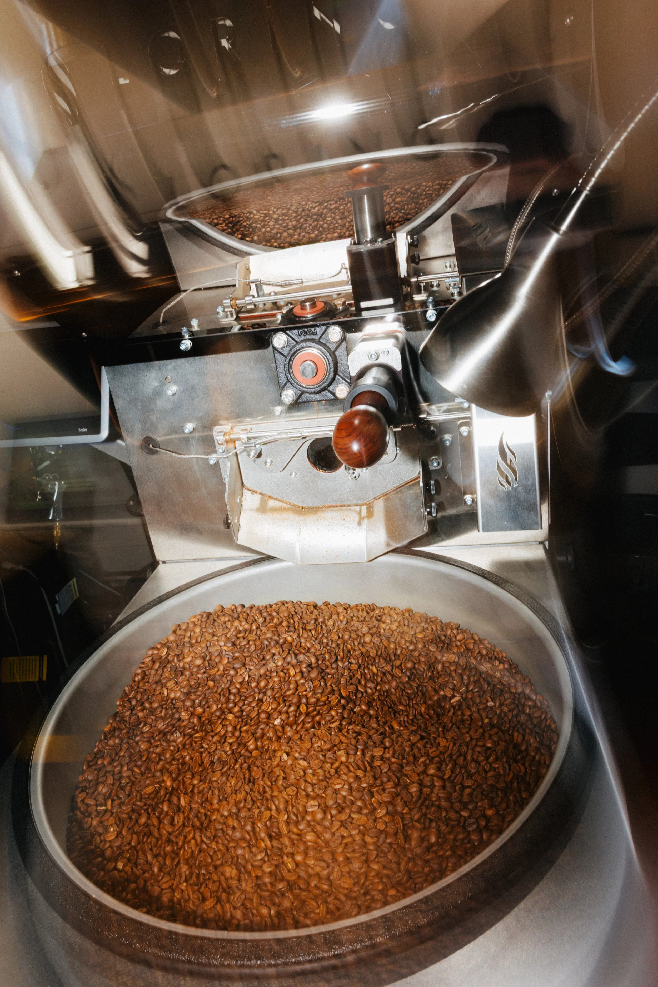 A close-up view of an industrial coffee roasting machine with roasted coffee beans inside.