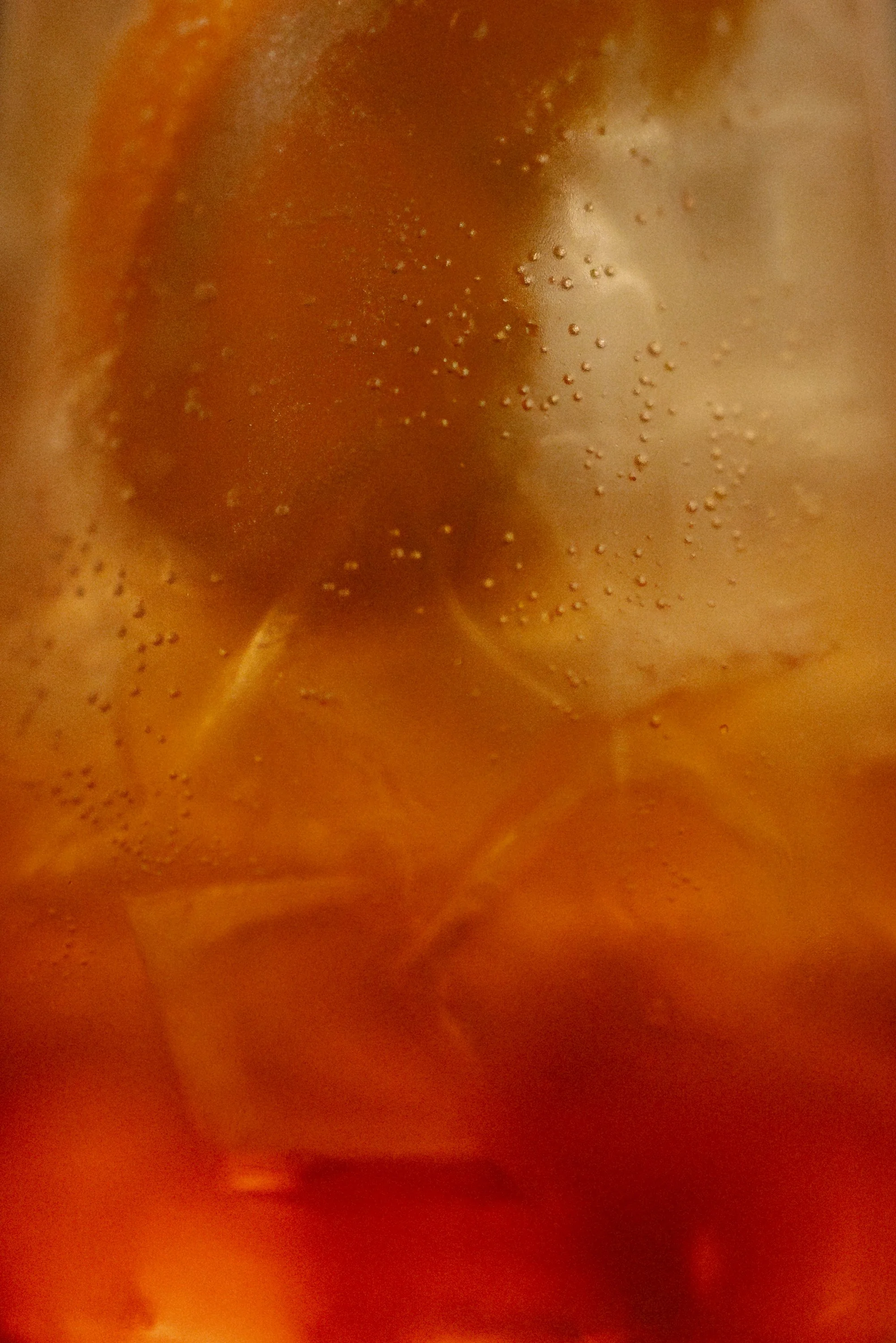 Close-up of a carbonated beverage with bubbles and caramel-colored liquid.