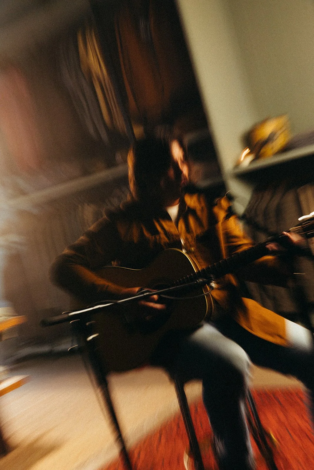 Person playing guitar in a dimly lit room with a blurred motion effect.