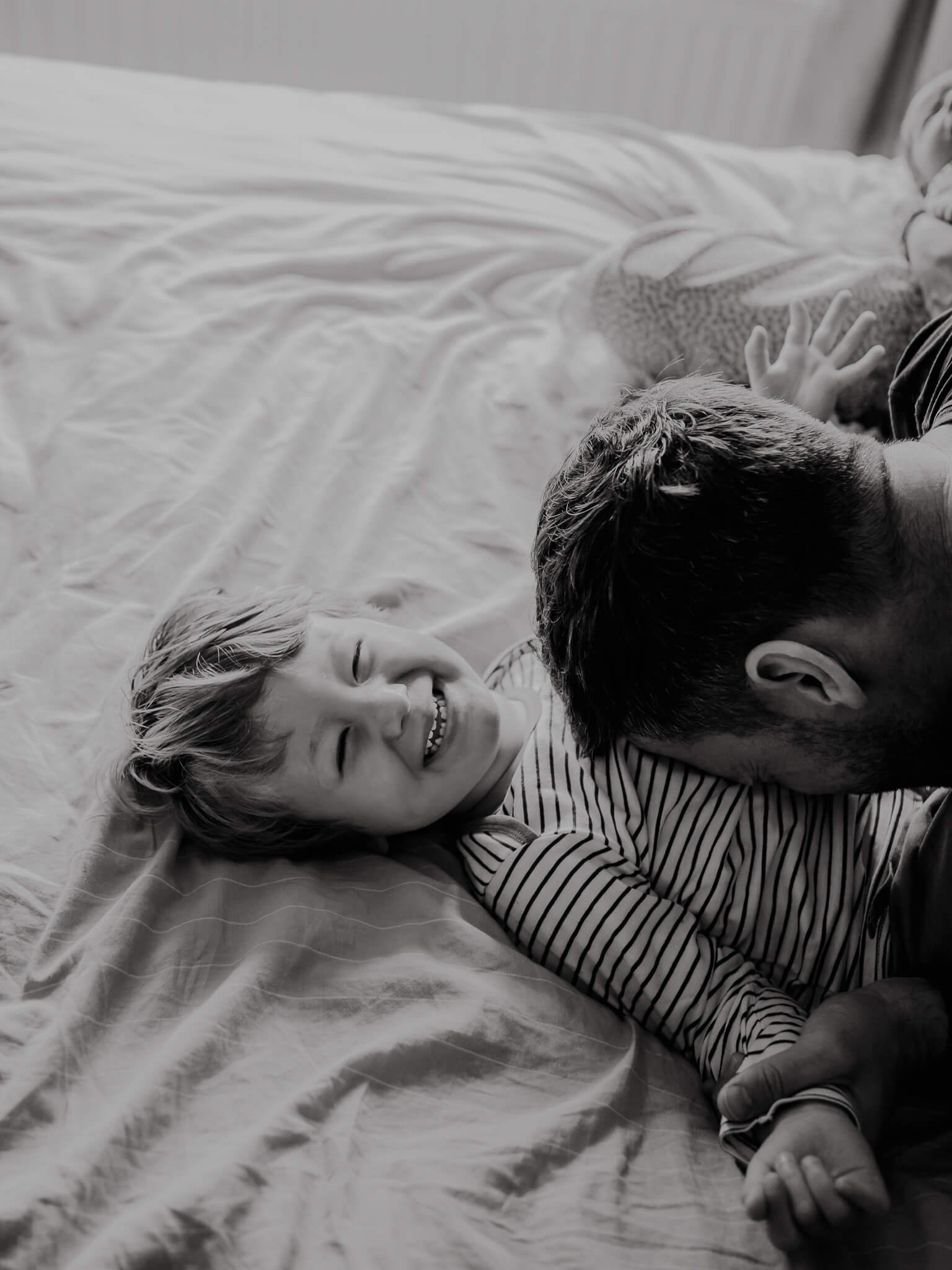 Dad tickling Toddler son who is smiling