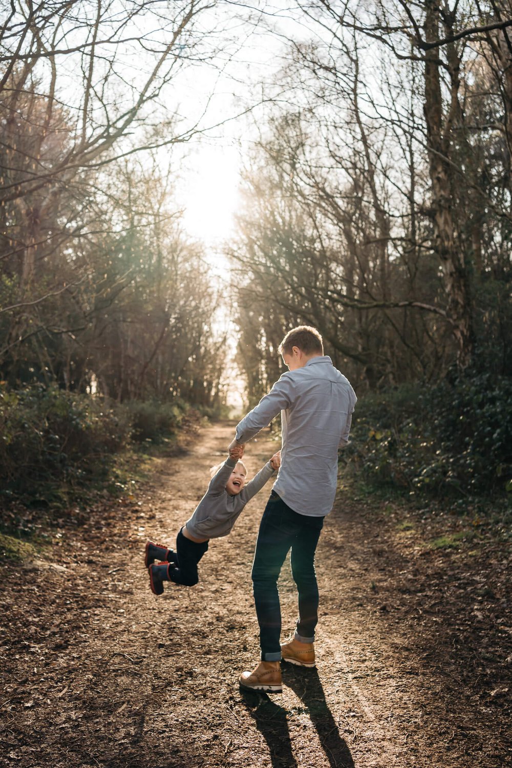Dad spinning son around by his hands at sunset