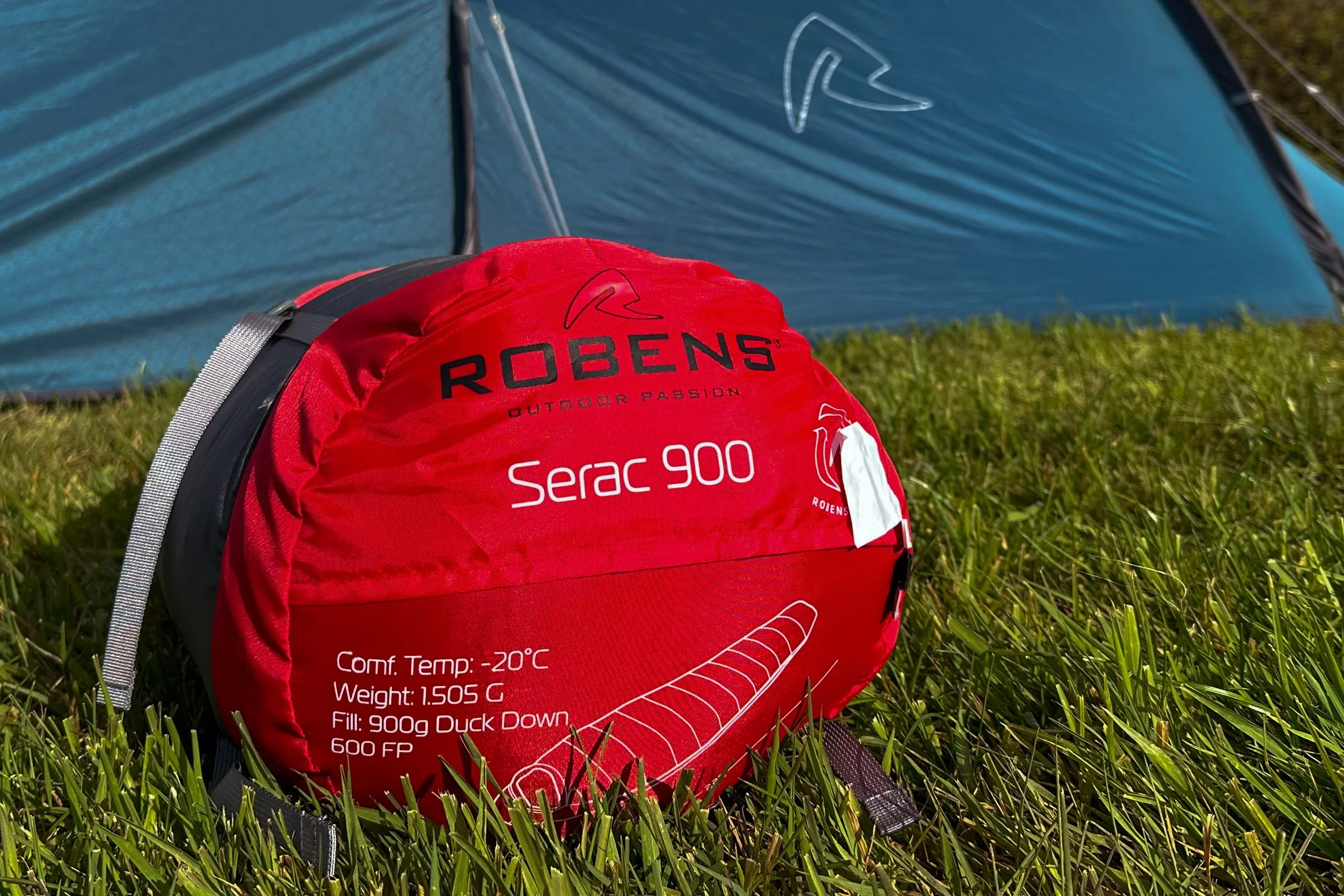 Red Robinson outdoor gear bag on grass with a tent in the background.