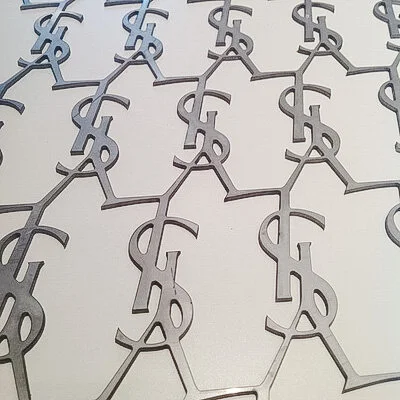 Close-up of multiple interlinked metallic dollar sign symbols arranged in rows.