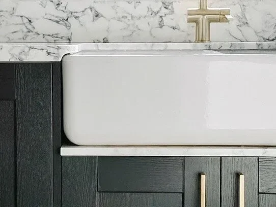 Belfast sink with marble surround, brass tap and dark timber cabinetry at a private residence in Tonbridge