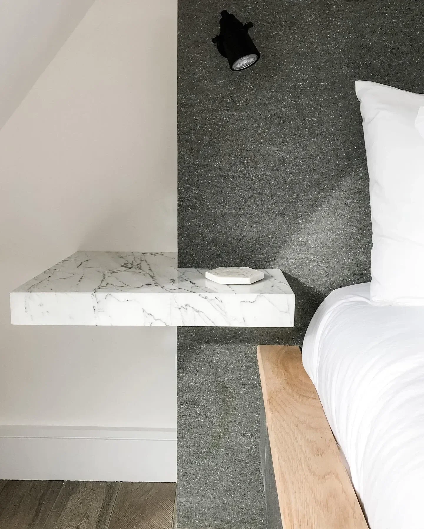 Floating marble bedside table with mitred edge detailing in a bedroom at a private residence in Tonbridge